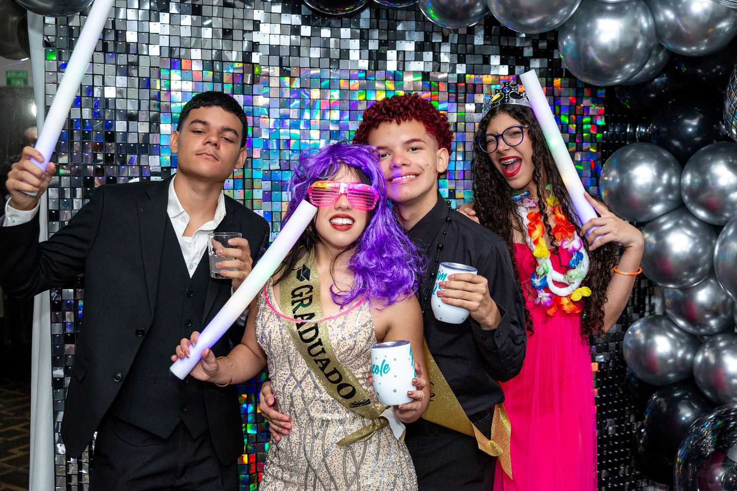 Group of friends enjoying a party with disco ball backdrop and sparkly decorations. graduation party