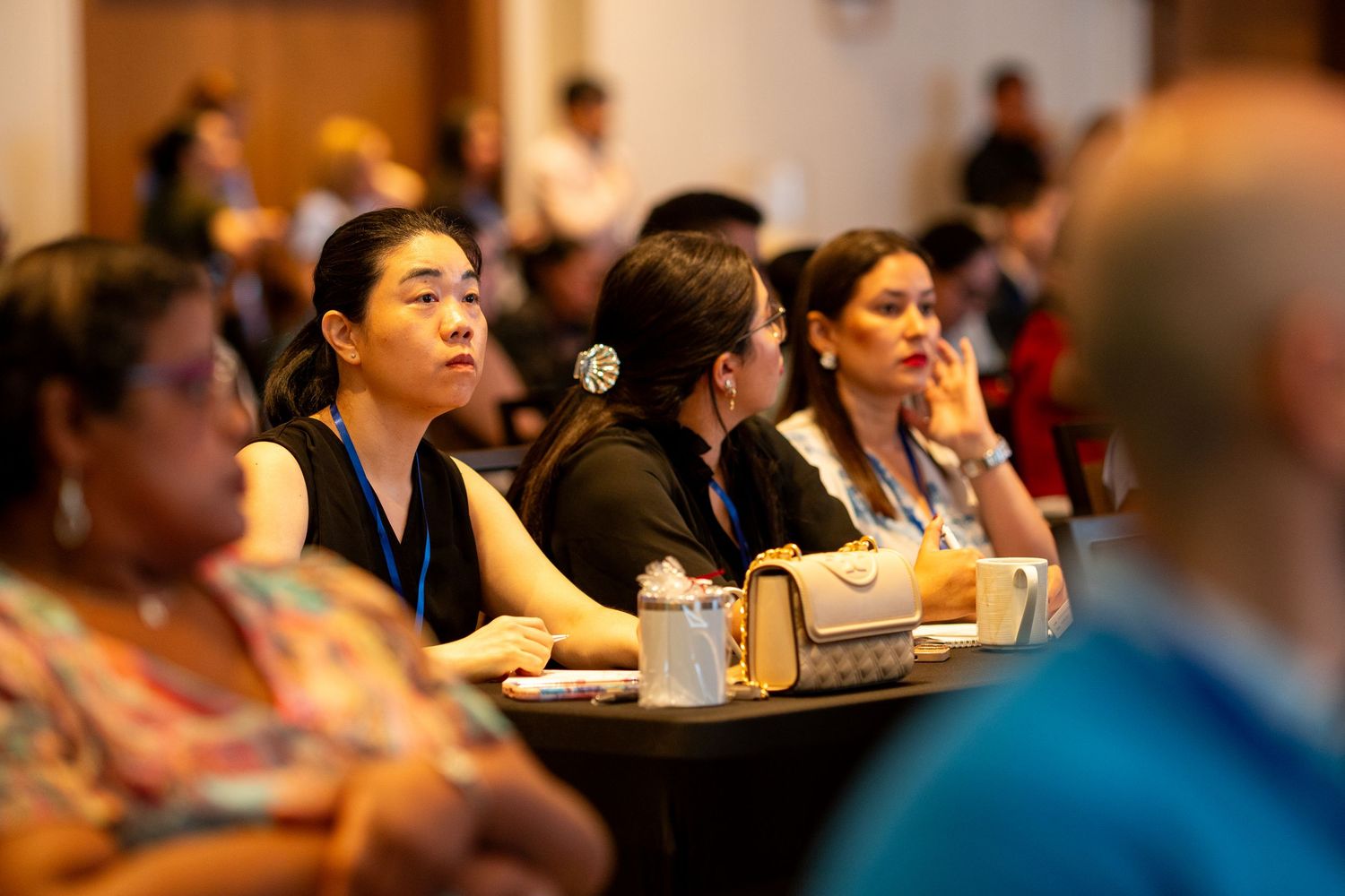 Diverse group of professionals attentively listening at a conference seminar session in a large meeting room.