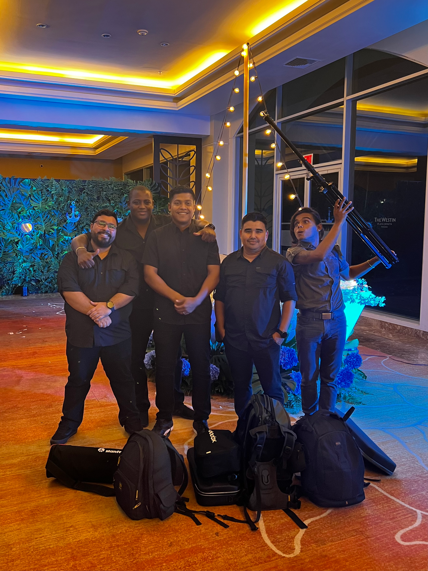 Team photo of event staff in dark uniforms gathered in a venue with ambient lighting.