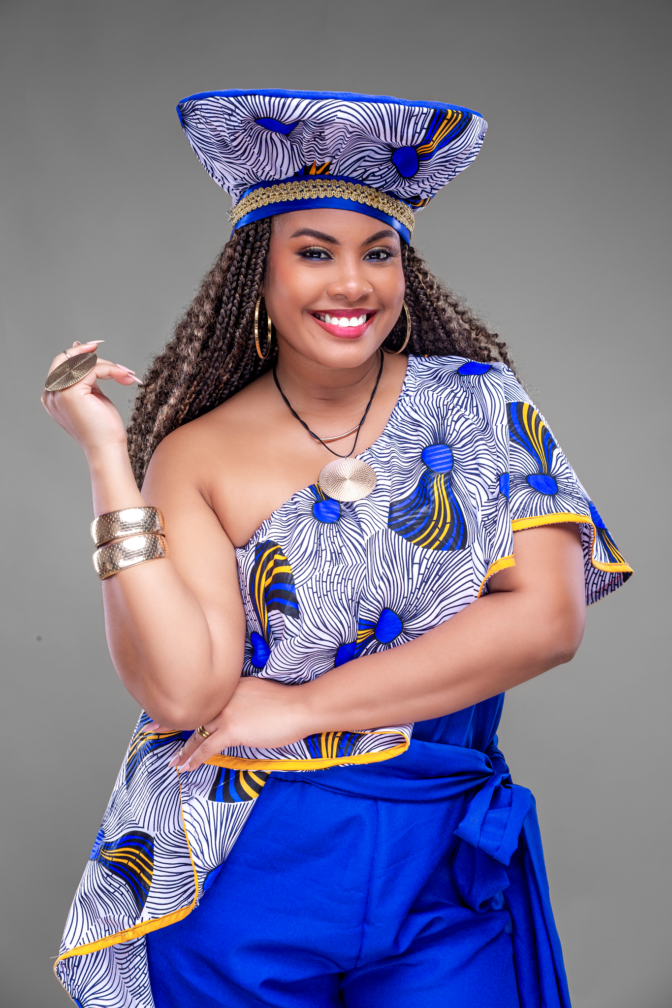 Model wearing traditional African blue and white patterned dress with matching headpiece and silver accessories.