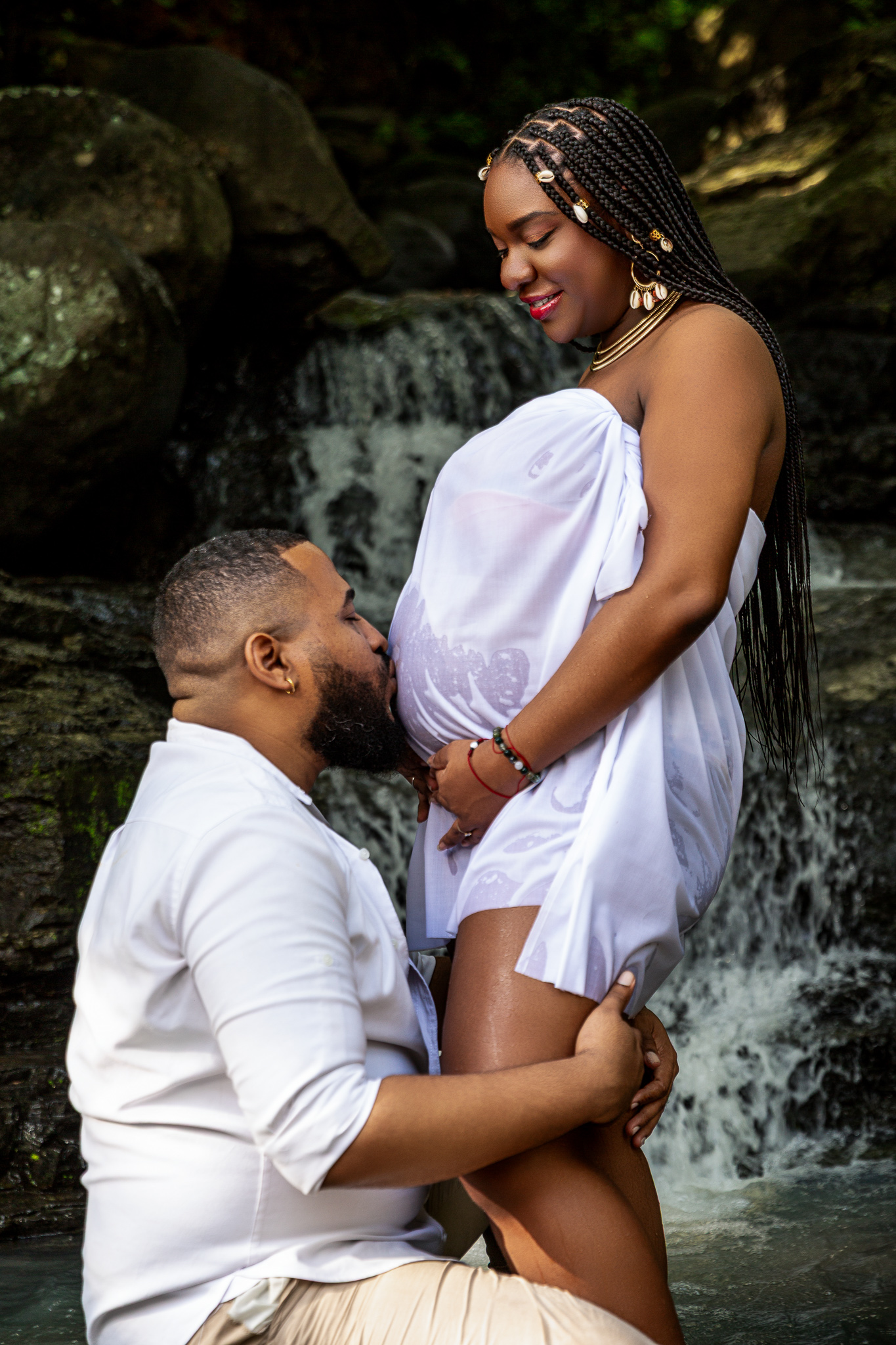 Tender maternity moment captured against waterfall backdrop.