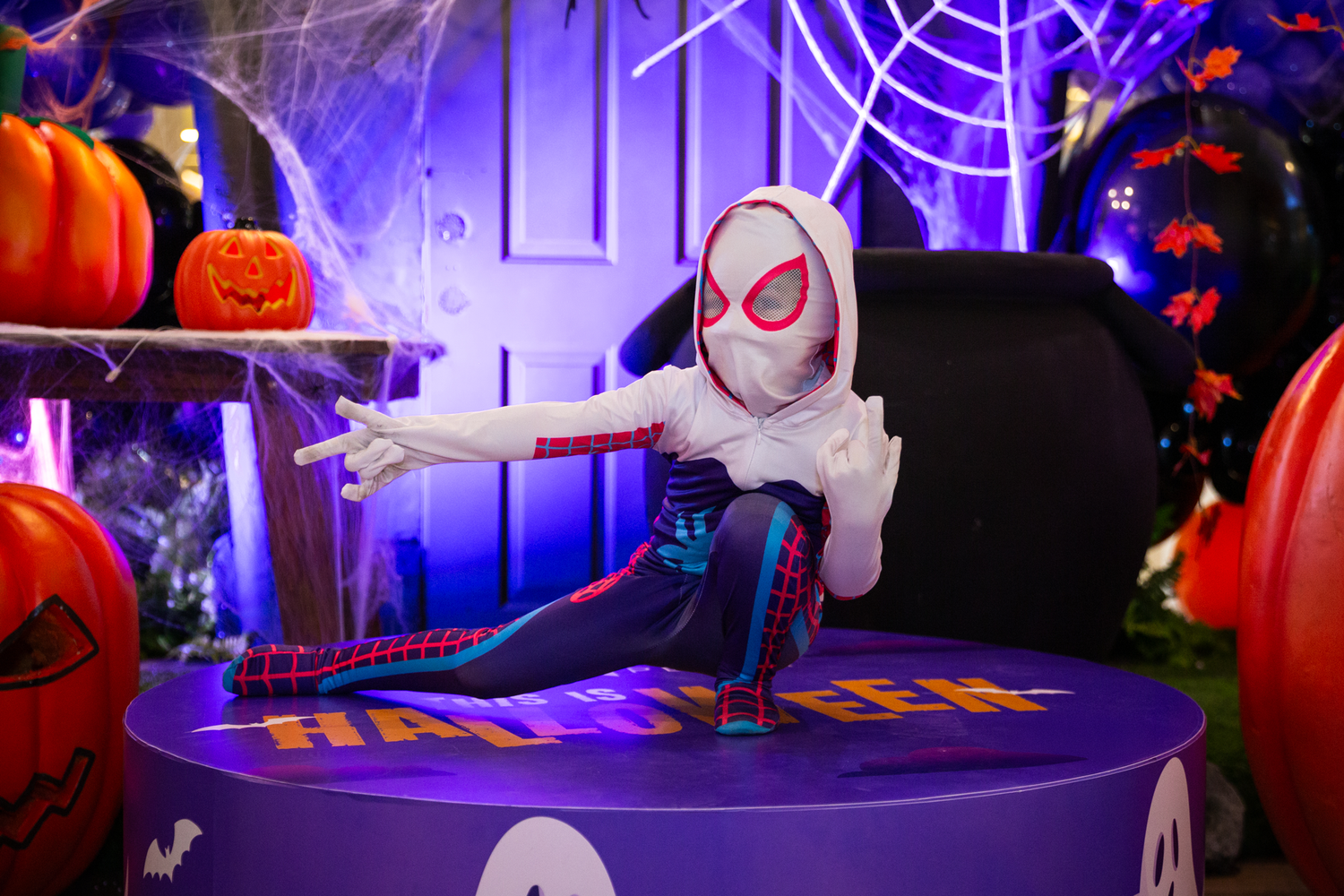 Halloween party setup with purple lighting, spider webs, and spooky decorations.