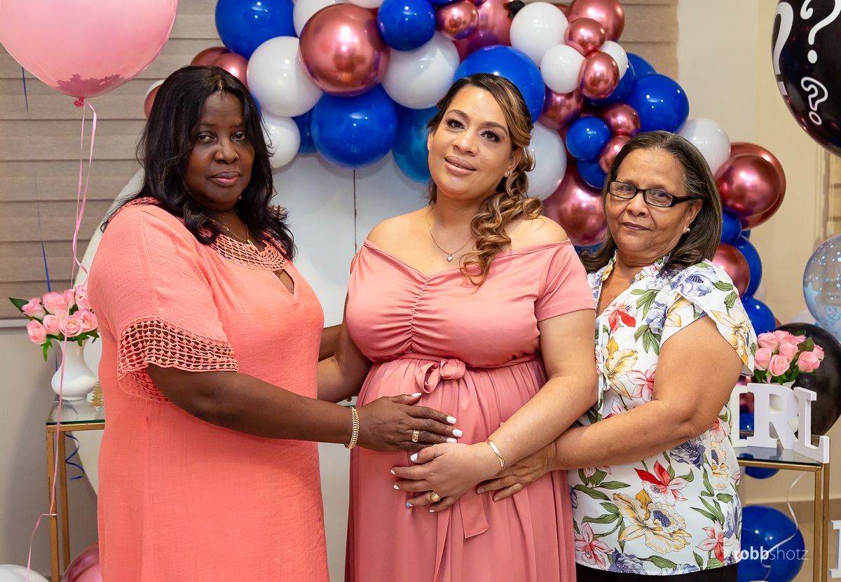 A group photo with pink and blue balloon decorations in the background.