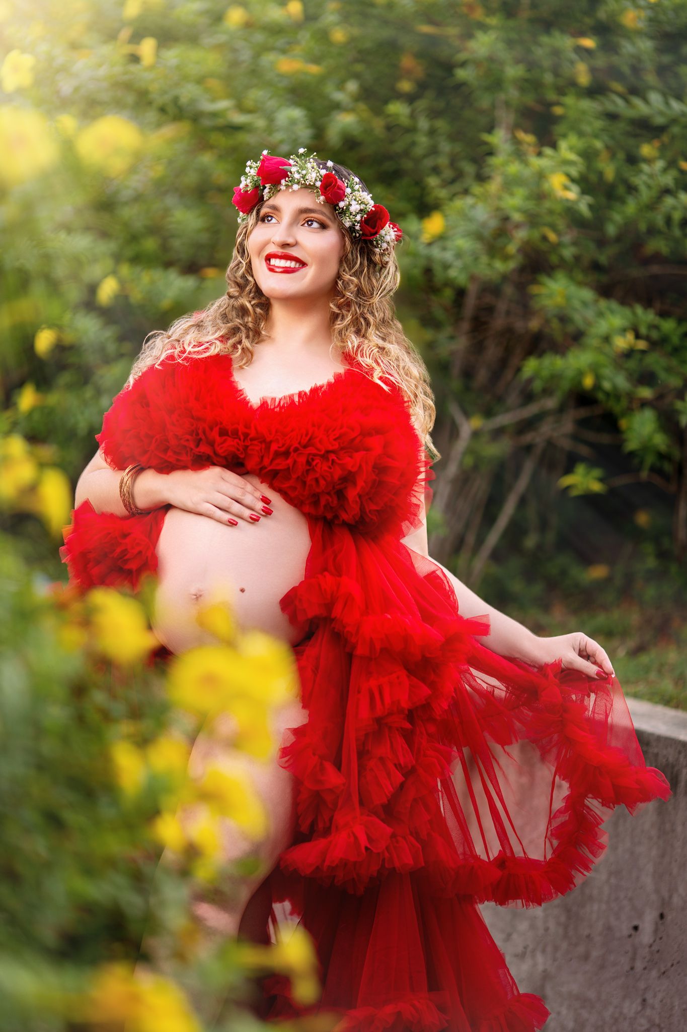 Artistic outdoor portrait featuring a flowing red tulle dress and floral crown against a soft natural background.