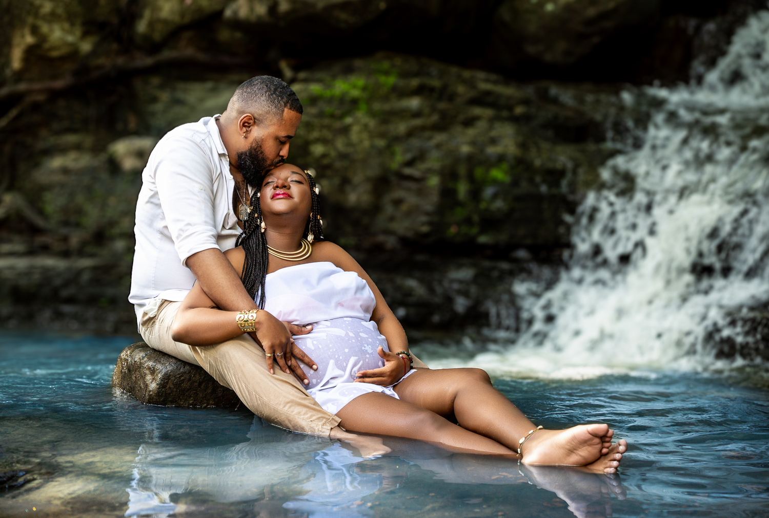 Intimate maternity portrait of couple relaxing by waterfall.