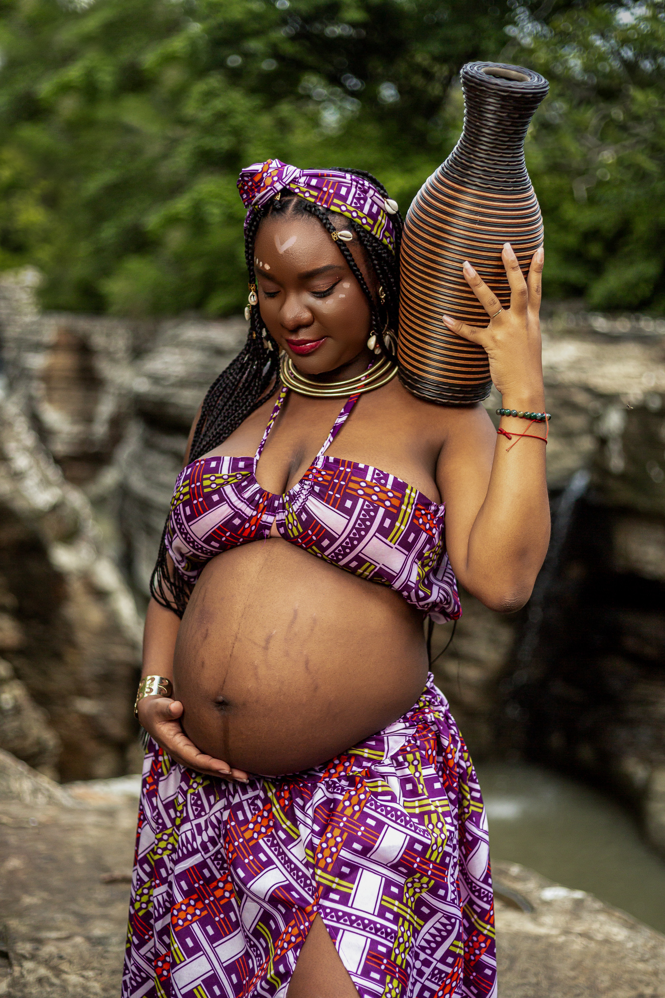 Artistic maternity portrait with decorative vase in African print attire.