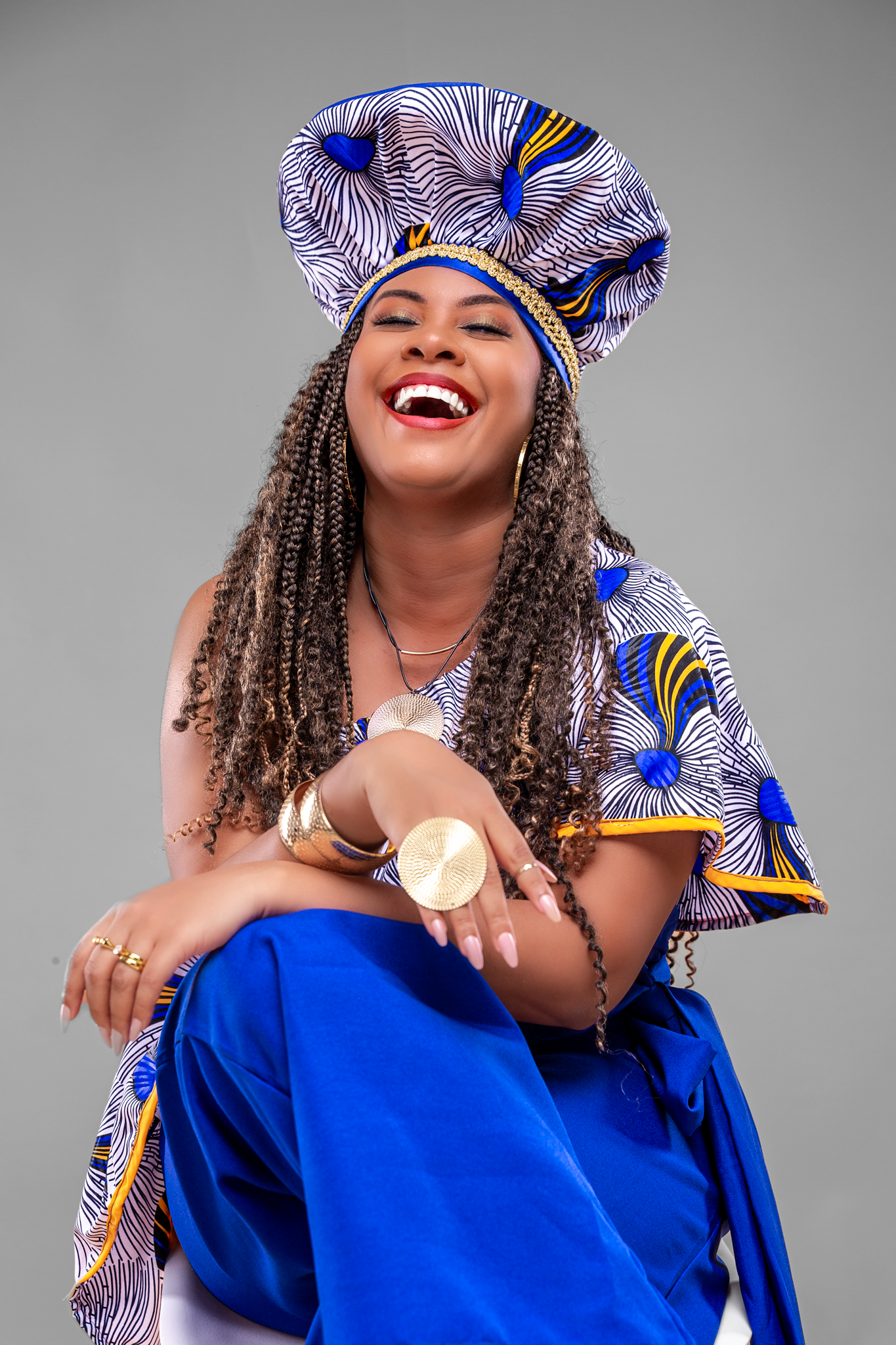 Joyful fashion poses showcasing blue African print ensemble against grey background.