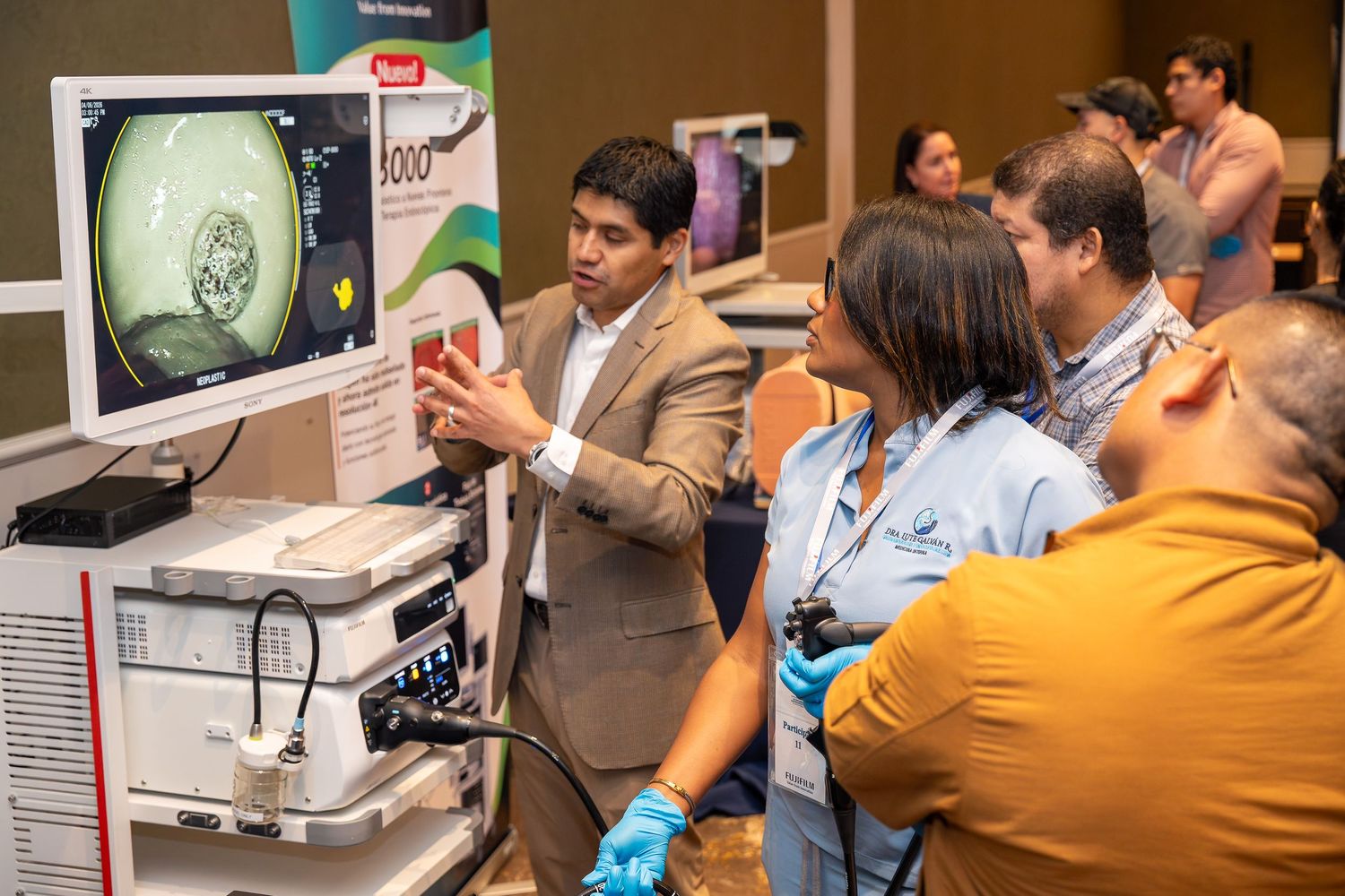 Medical professional demonstrates endoscopy equipment to colleagues at a healthcare technology exhibition.