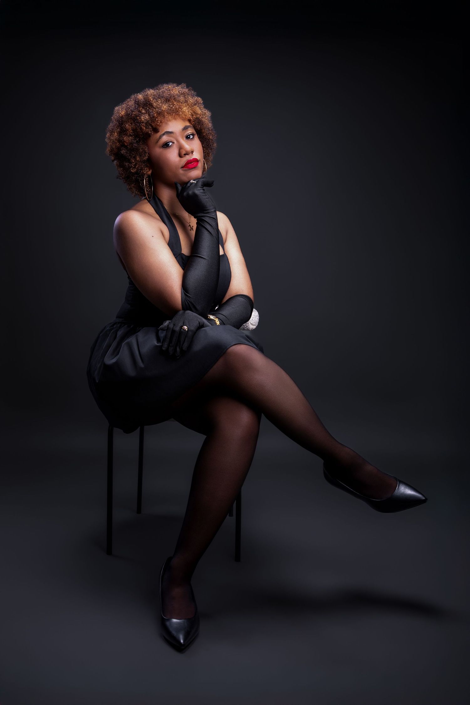 Artistic boudoir photography series featuring dramatic poses on a chair against a dark background with moody lighting.