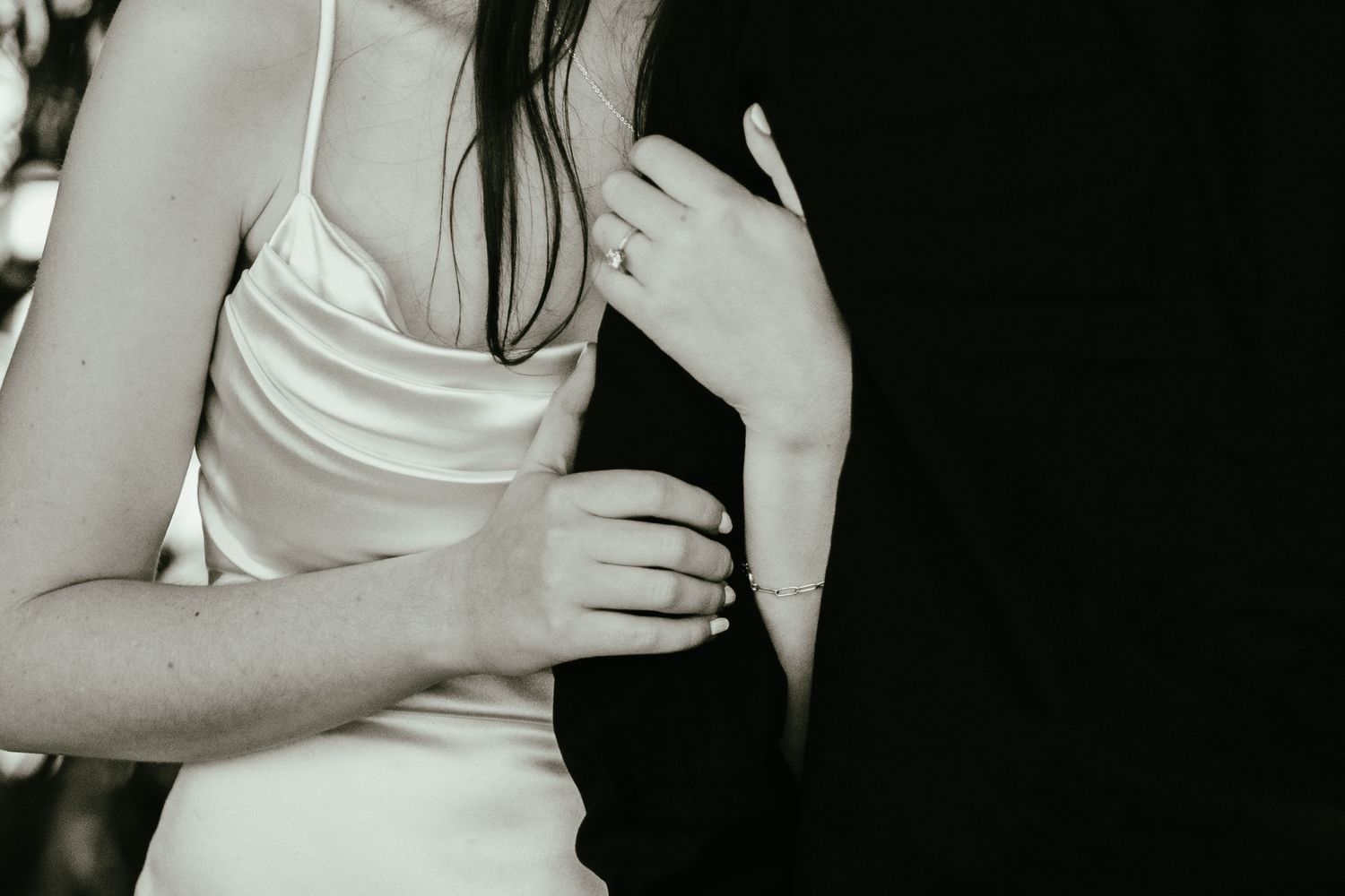 Black and white close-up of bride in silk slip dress holding groom's lapel during wedding day.