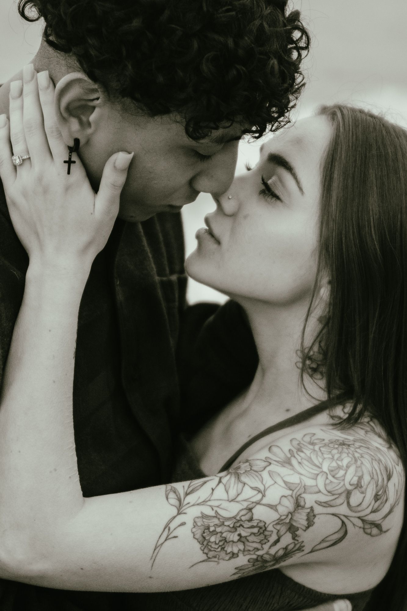A black and white portrait of a couple sharing an intimate almost-kiss close together.