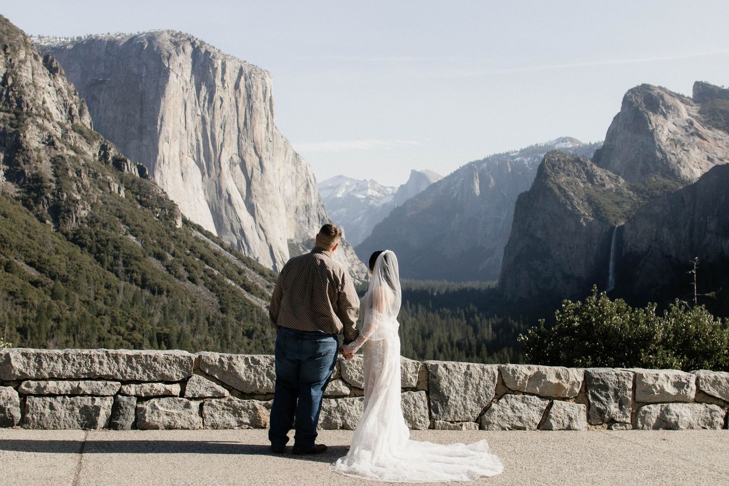 Bride and groom holding hands overlooking Yosemite Valley tunnel view scenic overlook.