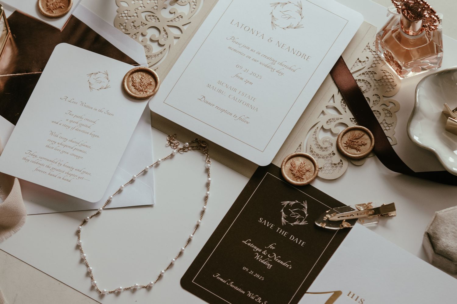 Elegant wedding stationery flat lay with gold wax seals, pearl necklace, and save the date card.