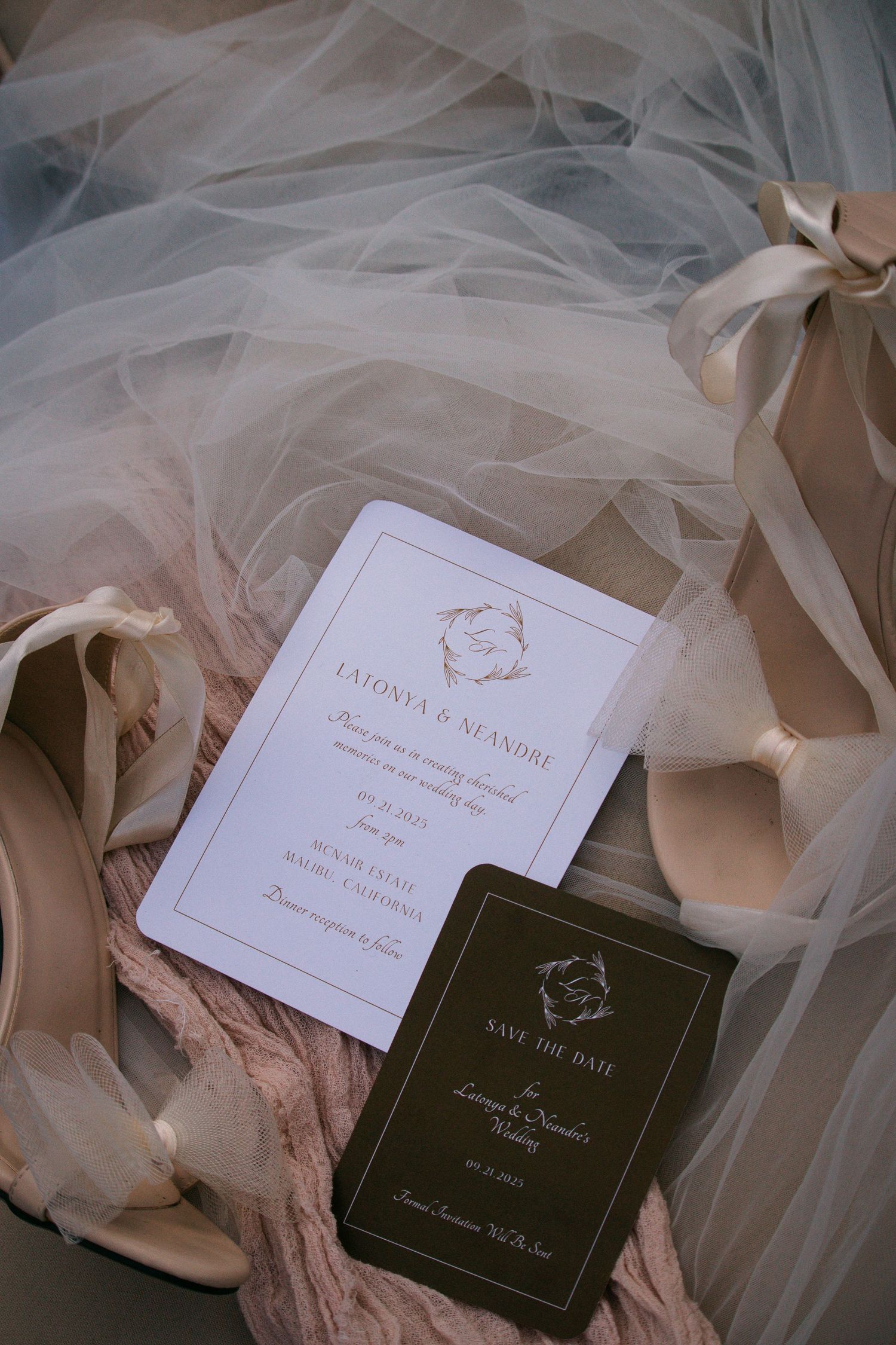 Wedding invitation suite with gold script on tulle fabric beside nude heels and save the date card.