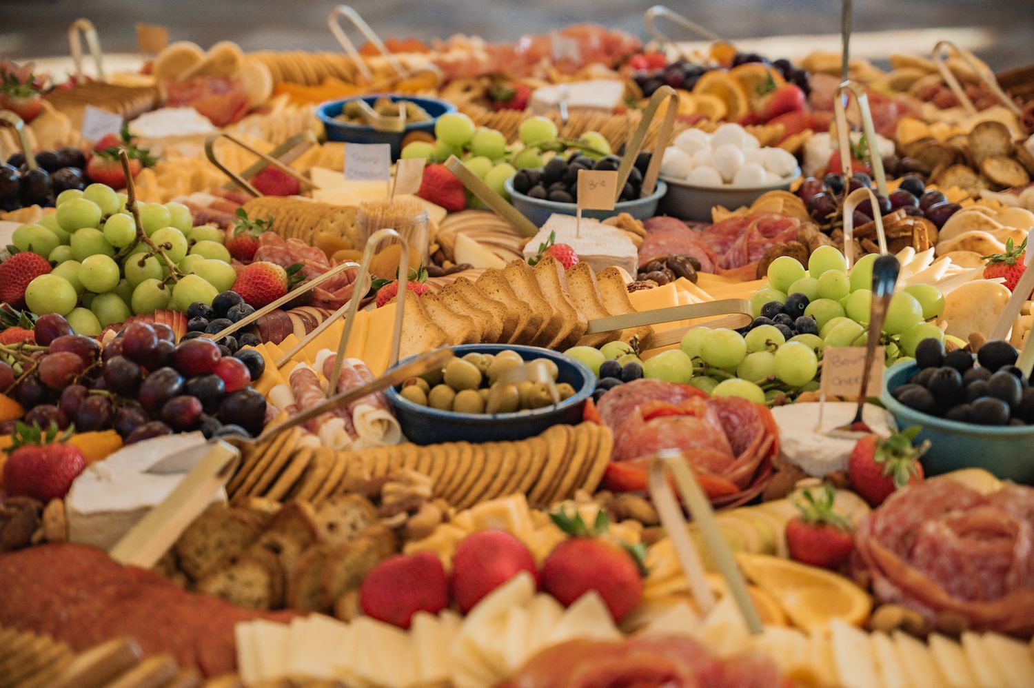 Elegant charcuterie board with grapes, crackers, cheeses, meats, olives, and strawberries for entertaining.