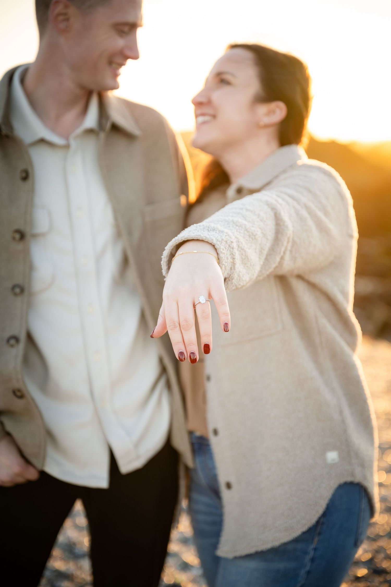 A couple shares an intimate moment at sunset wearing casual clothing in warm natural lighting.