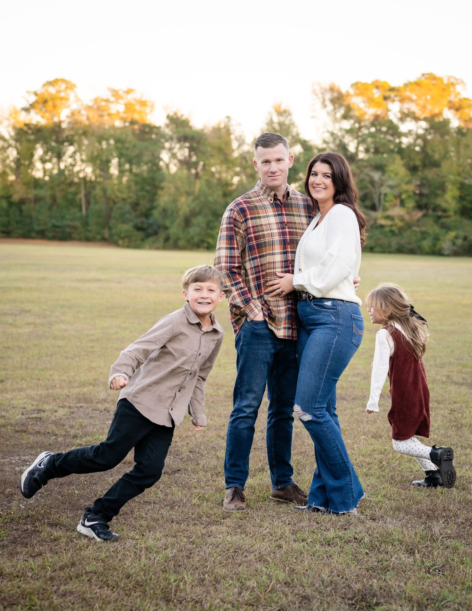 Family plays together in a grassy field during golden hour, creating a playful sequence of falling motions.