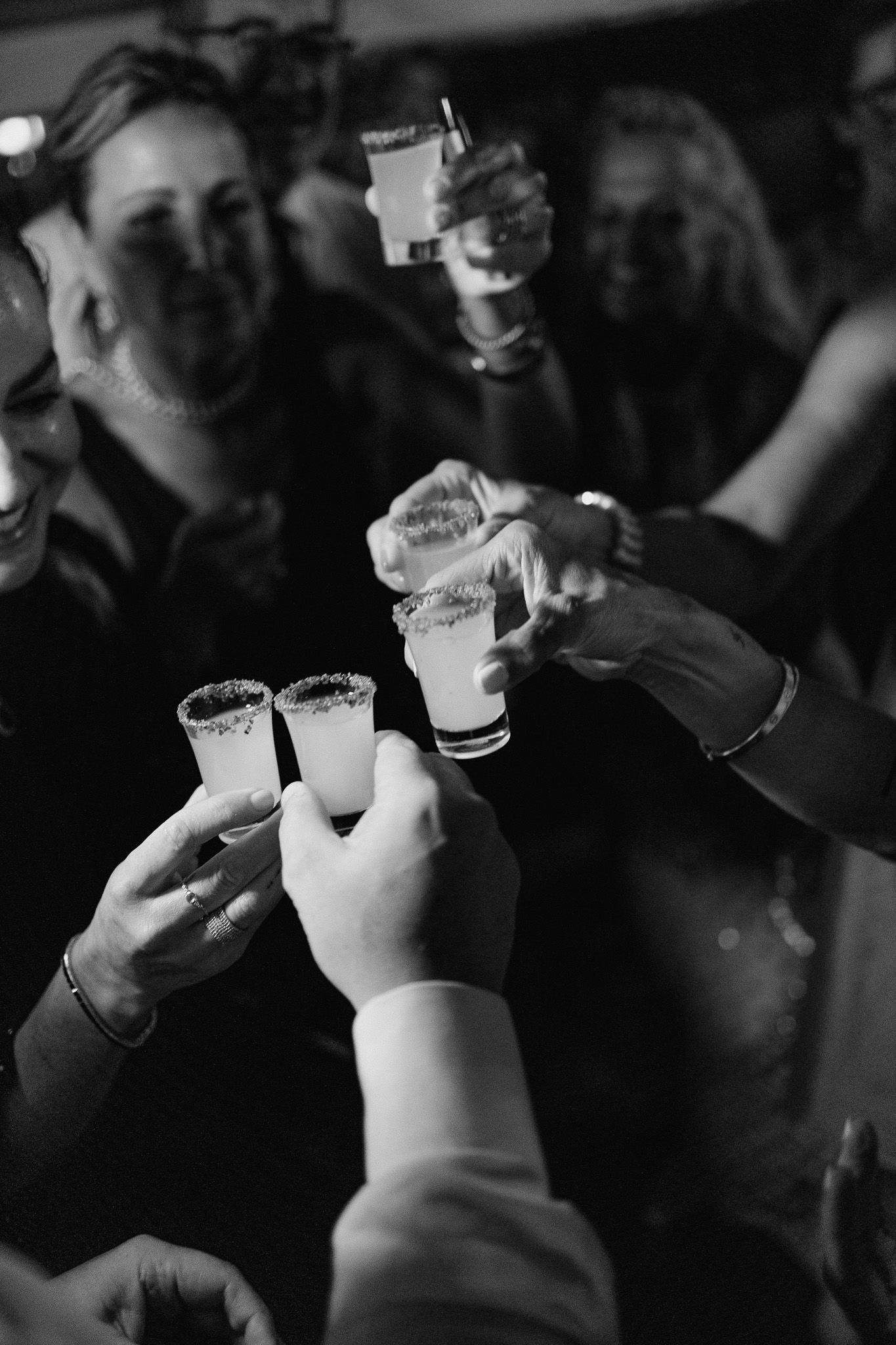 Black and white shot of friends toasting with small glasses at a celebration.