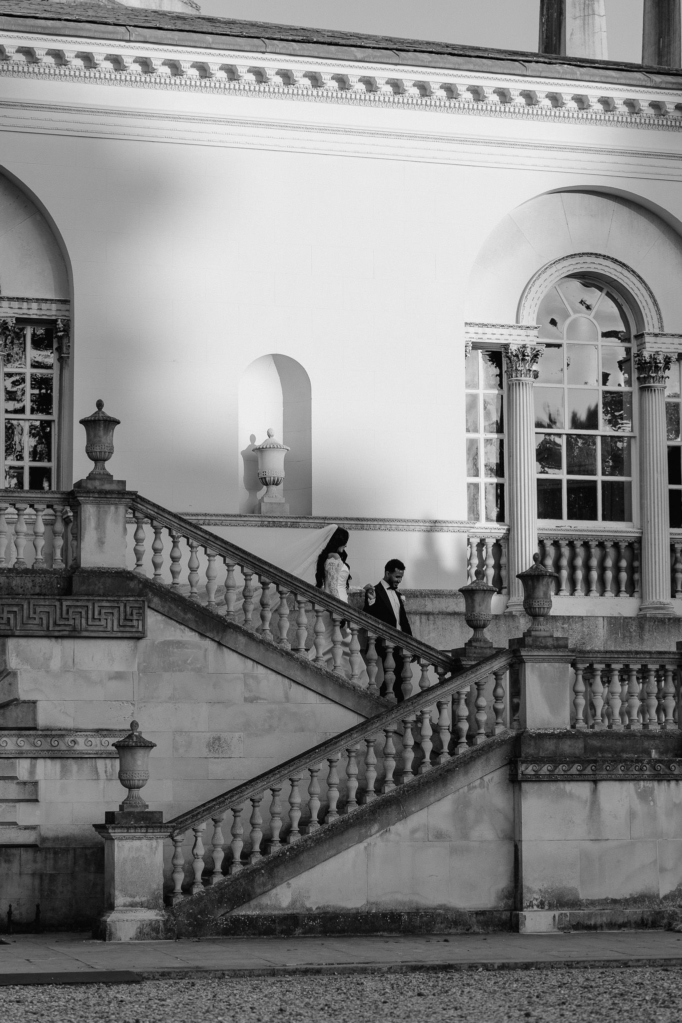 Black and white photo of wedding guests ascending an ornate stone staircase in a historic building.