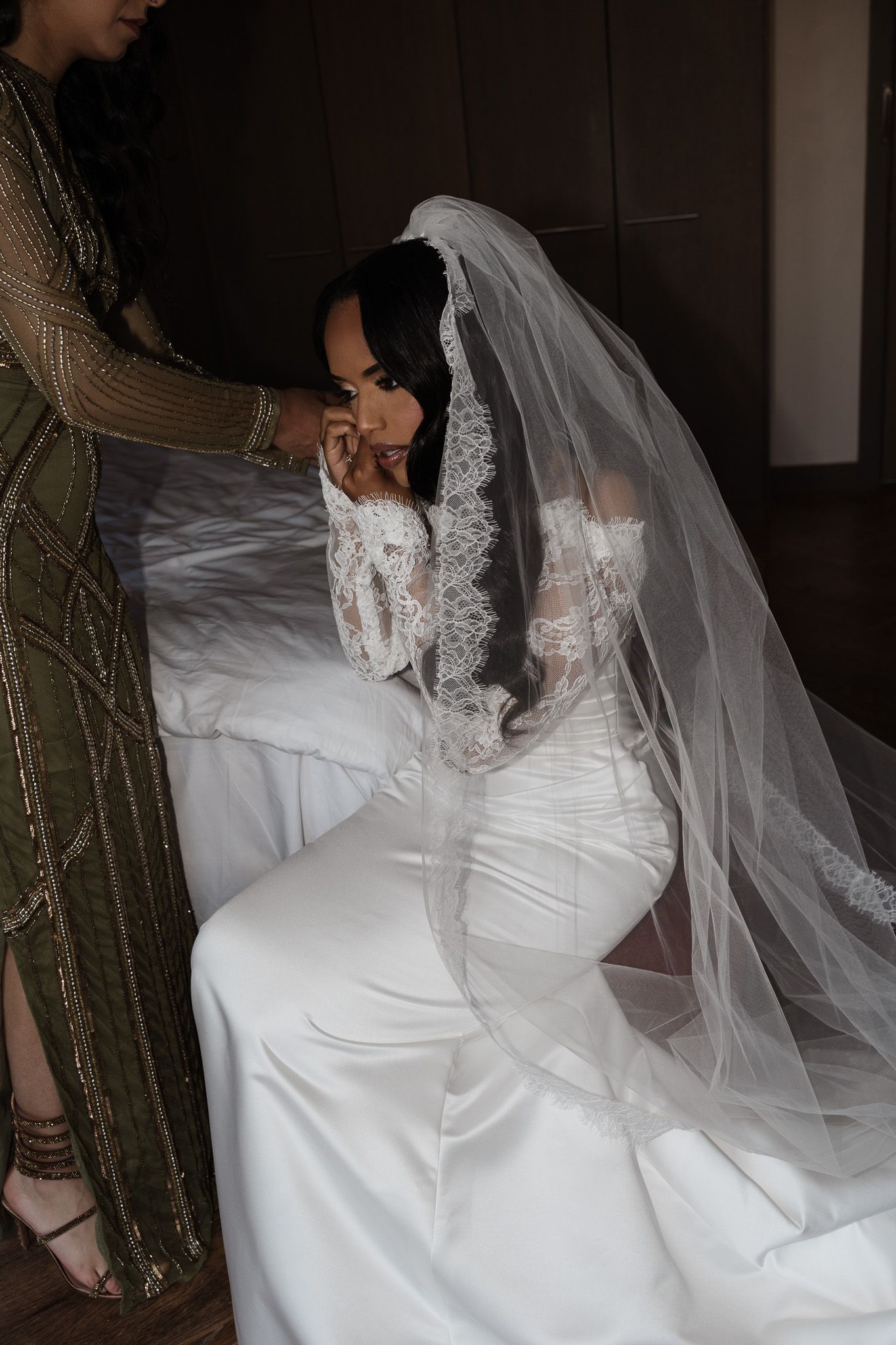 Intimate moment of a bride in a lace wedding gown and veil getting ready for her ceremony.
