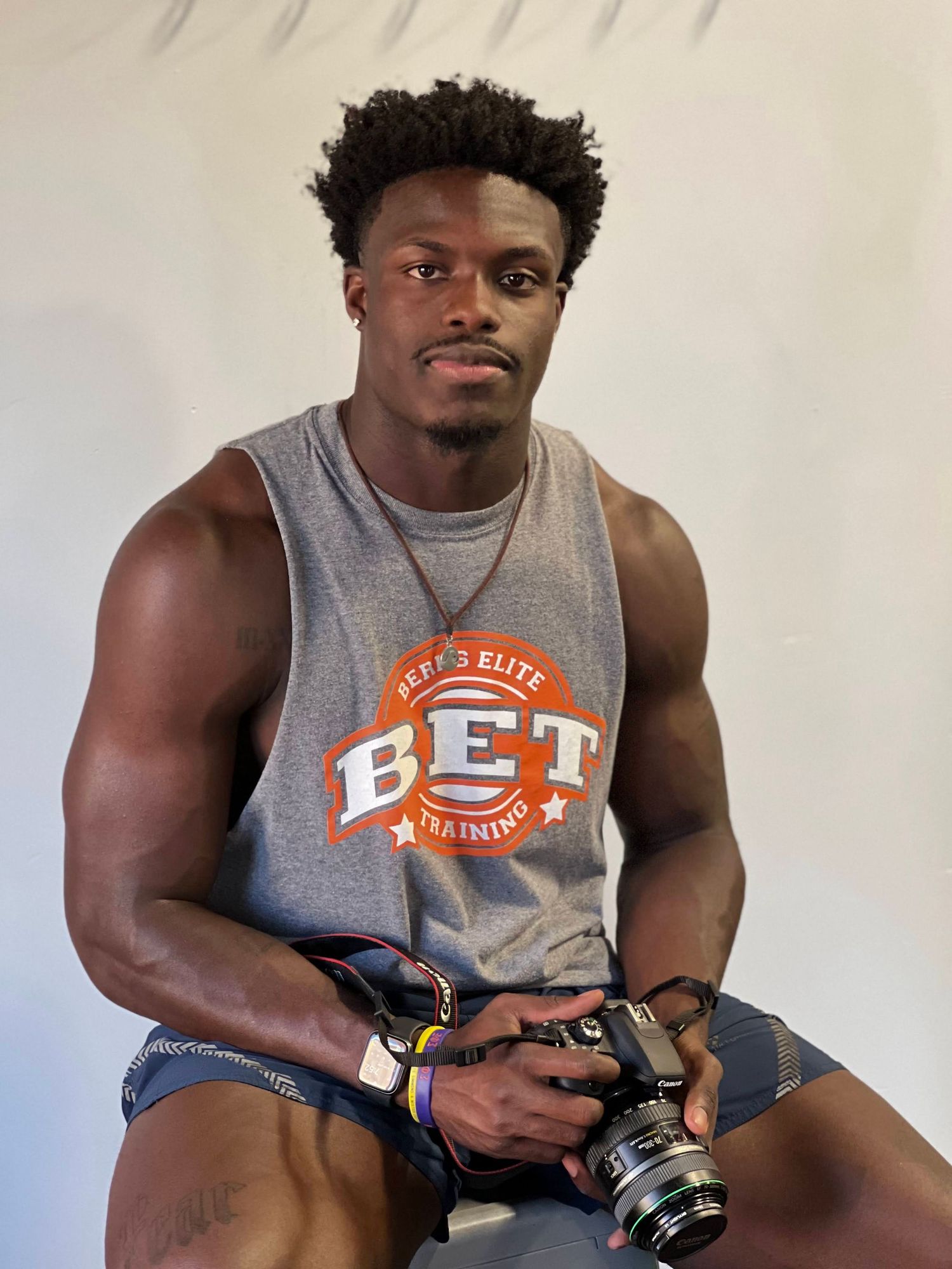 A person wearing an orange t-shirt smiles and poses with a digital camera in a series of candid shots.