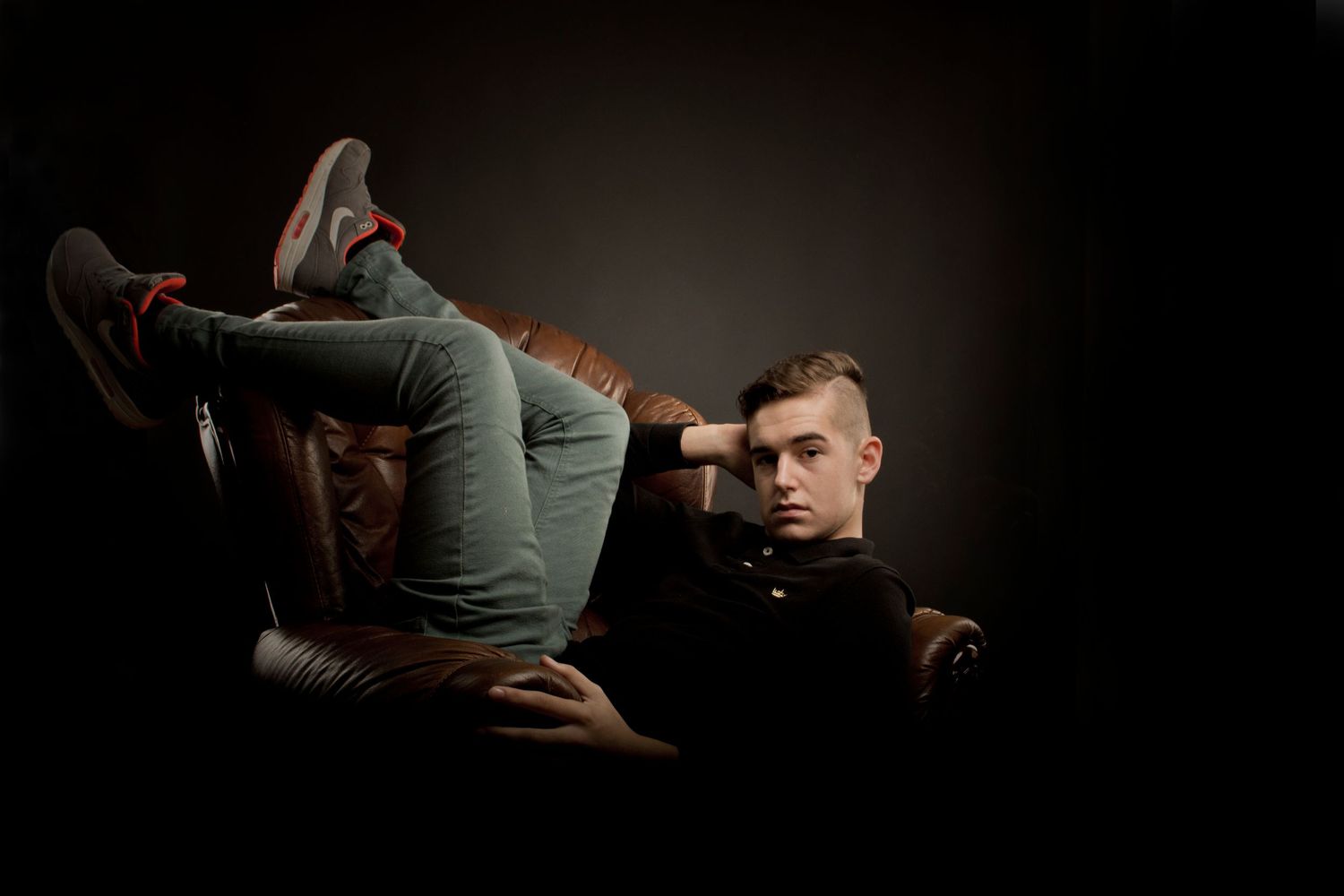 Young man in casual wear reclining in dark studio with a woman lying across his lap.