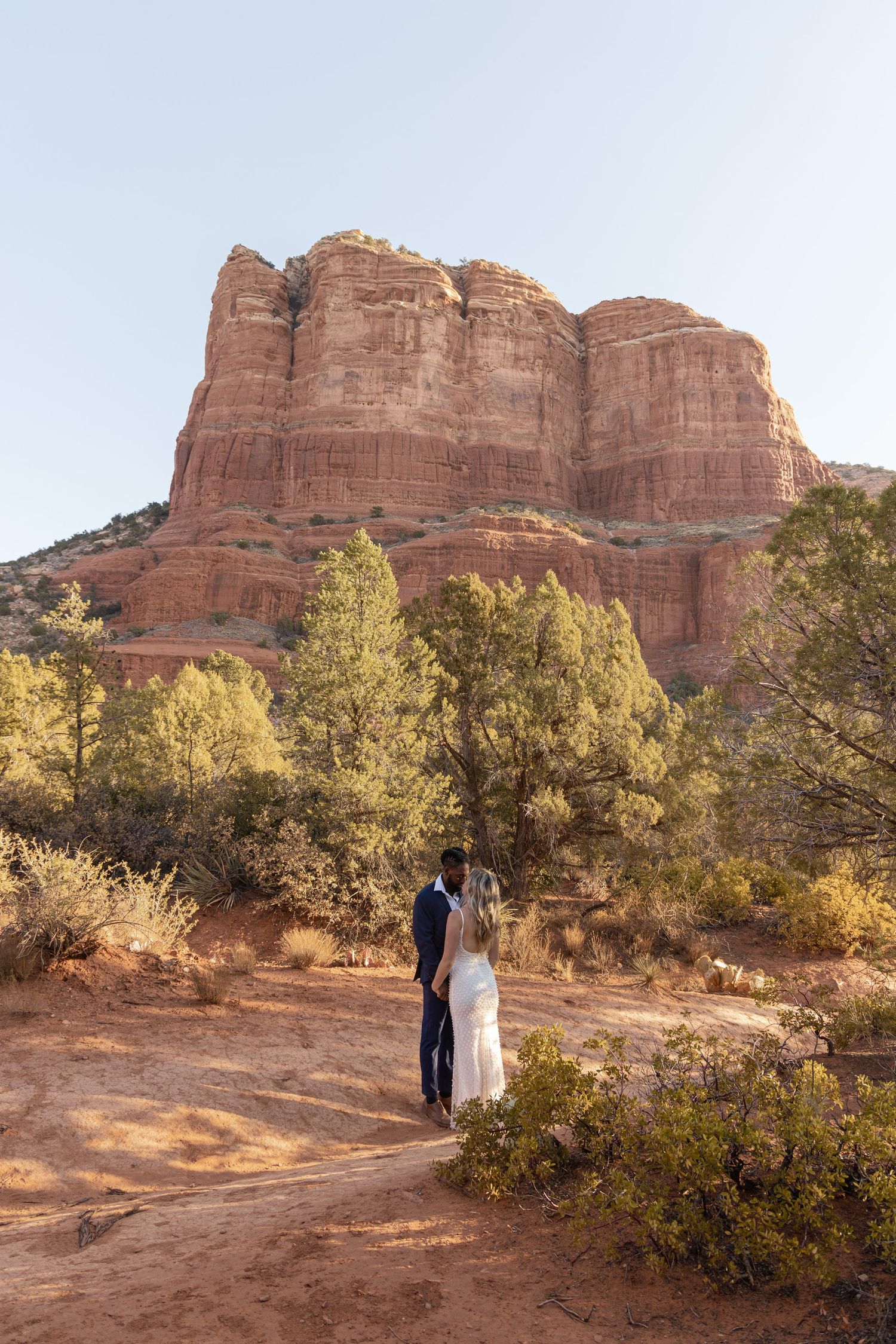 A couple stands together against the backdrop of majestic red rock formations at Cathedral Rock in Sedona, Arizona.