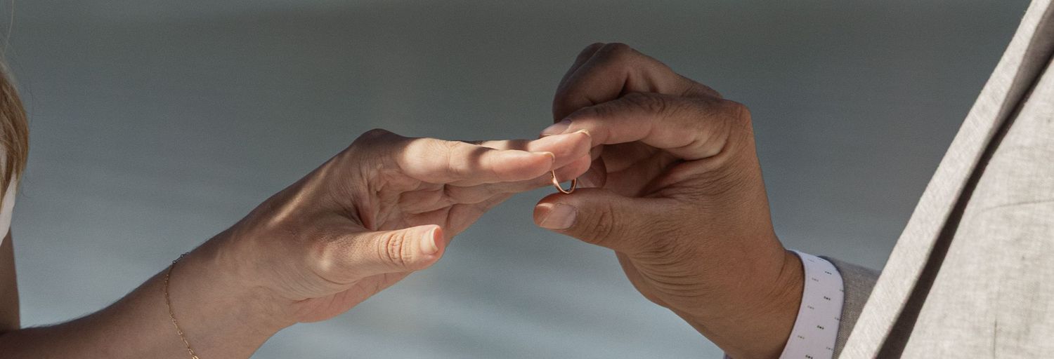 Two hands carefully exchanging a small pill or medication in a close-up view.