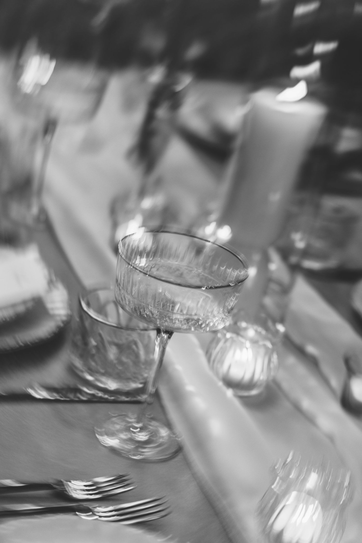 Elegant glass stemware and table settings arranged on a dining table in black and white photography.