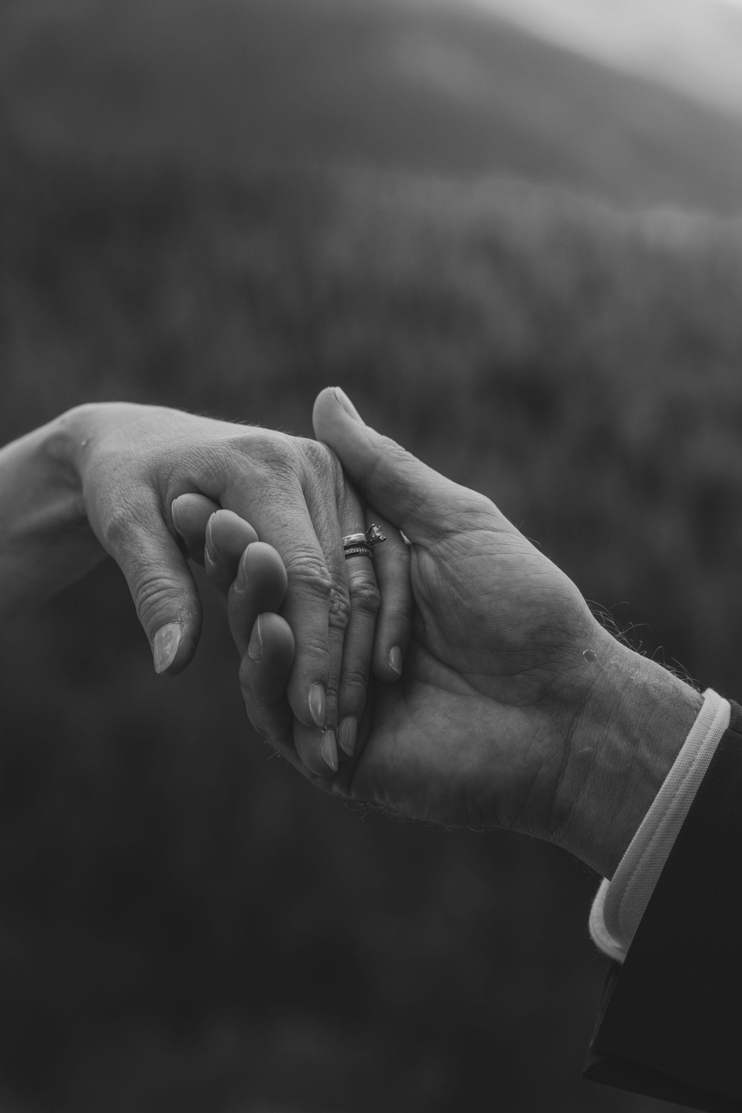 Two hands reaching towards each other in a black and white photograph showing an intimate connection between people.