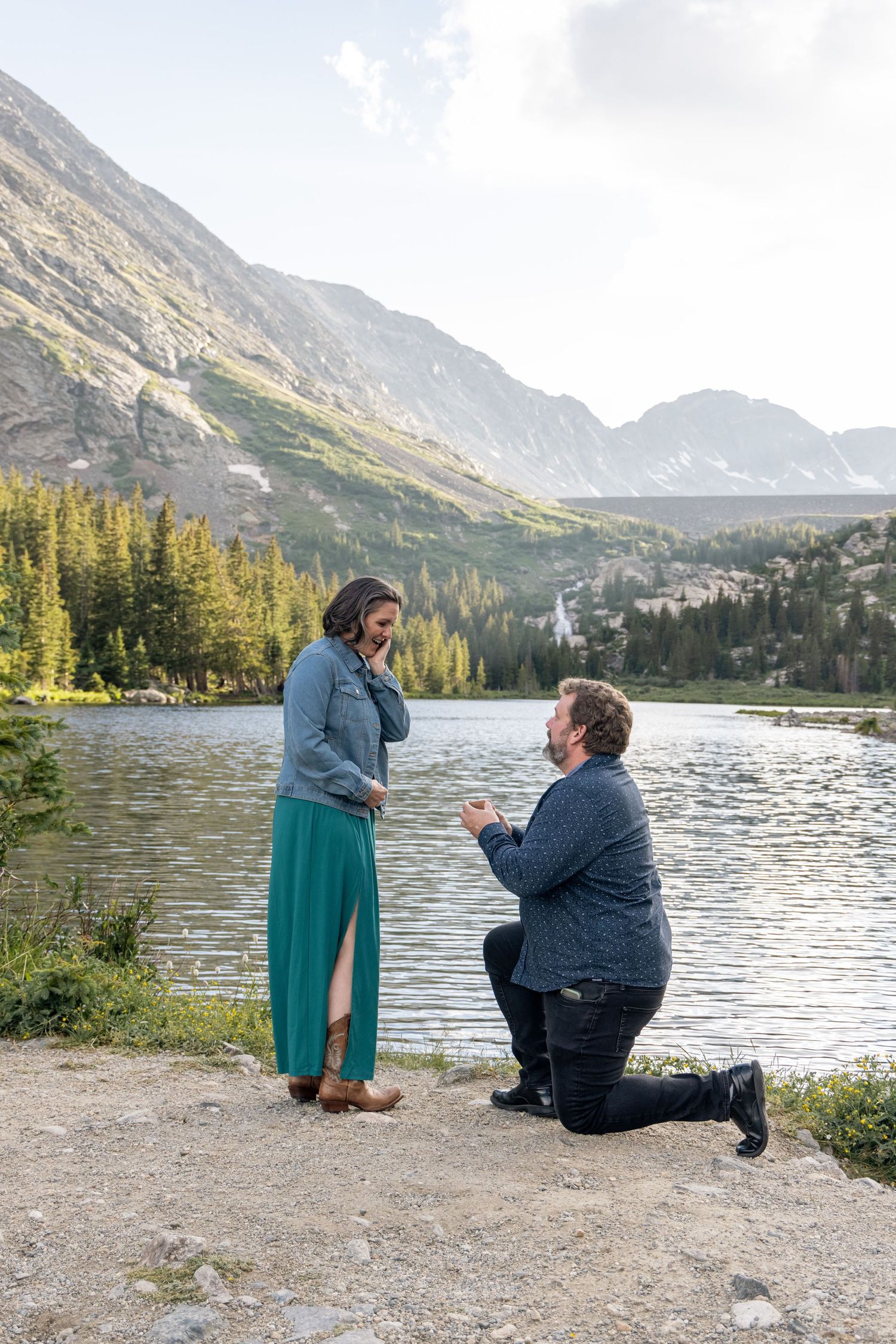 A romantic mountain proposal scene with stunning alpine lake and peaks as backdrop in serene wilderness setting.