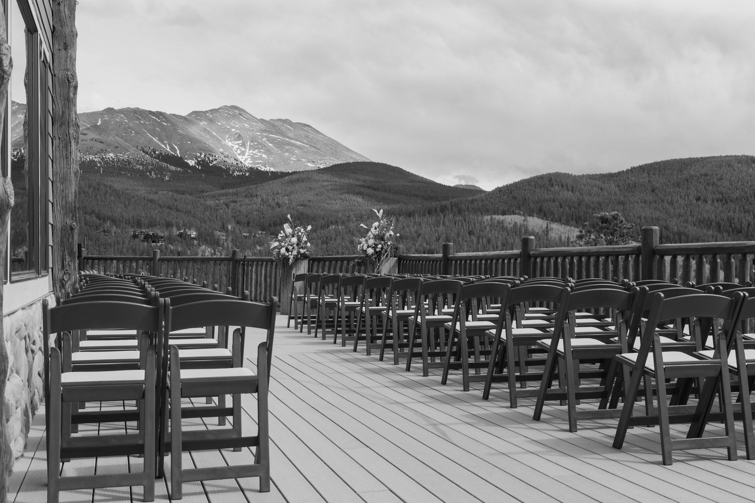 Black and white outdoor wedding ceremony setup on a mountain deck with rows of chairs and scenic Rocky Mountain views.