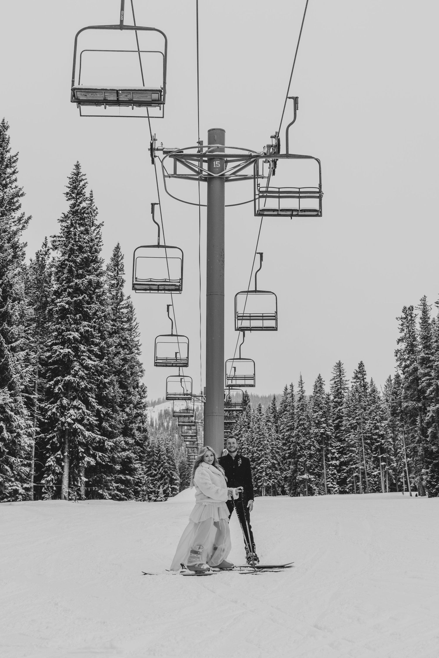 Black and white winter wedding photos show couple in snowy mountain setting with ski lift chairs in background.