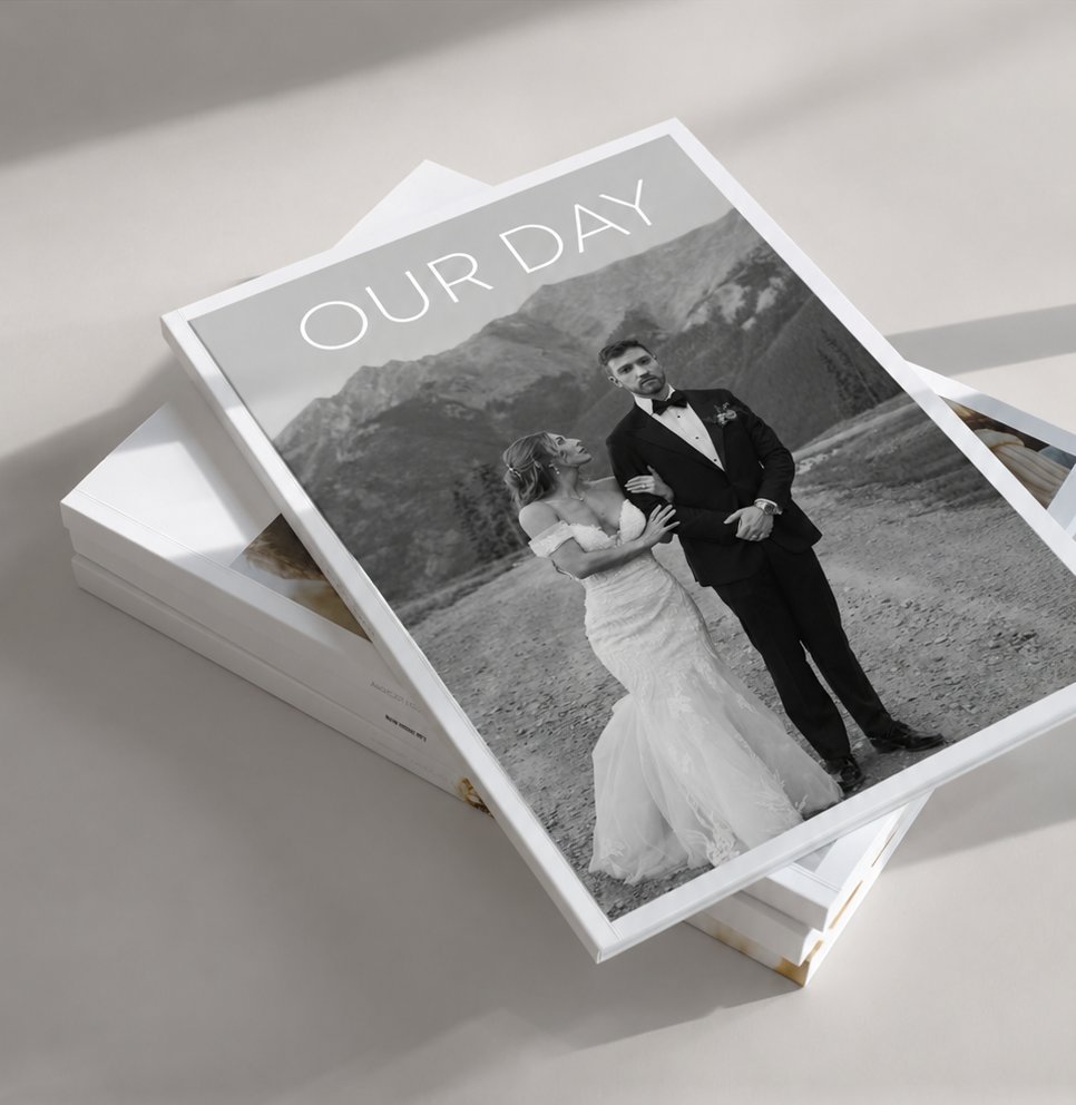 Black and white wedding photo book with couple embracing, titled Our Day, set against mountain backdrop.