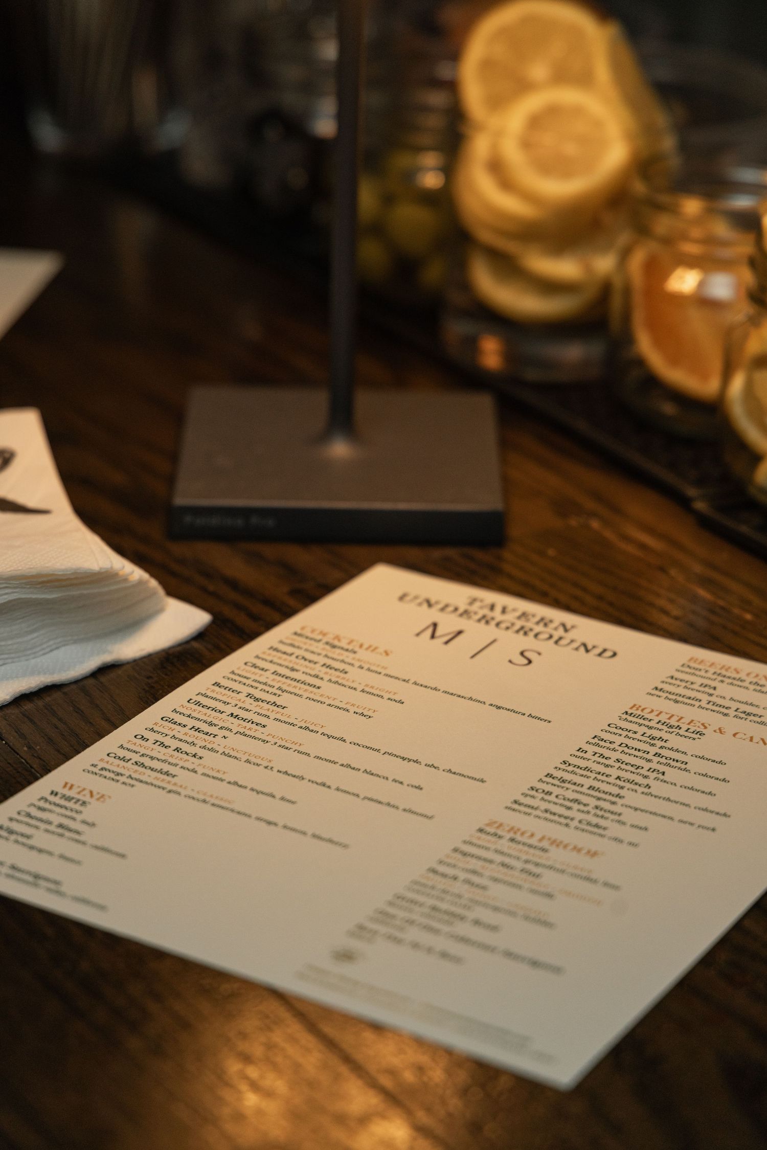 A series of restaurant menus displayed on a dark wooden table with warm lighting and shallow depth of field.