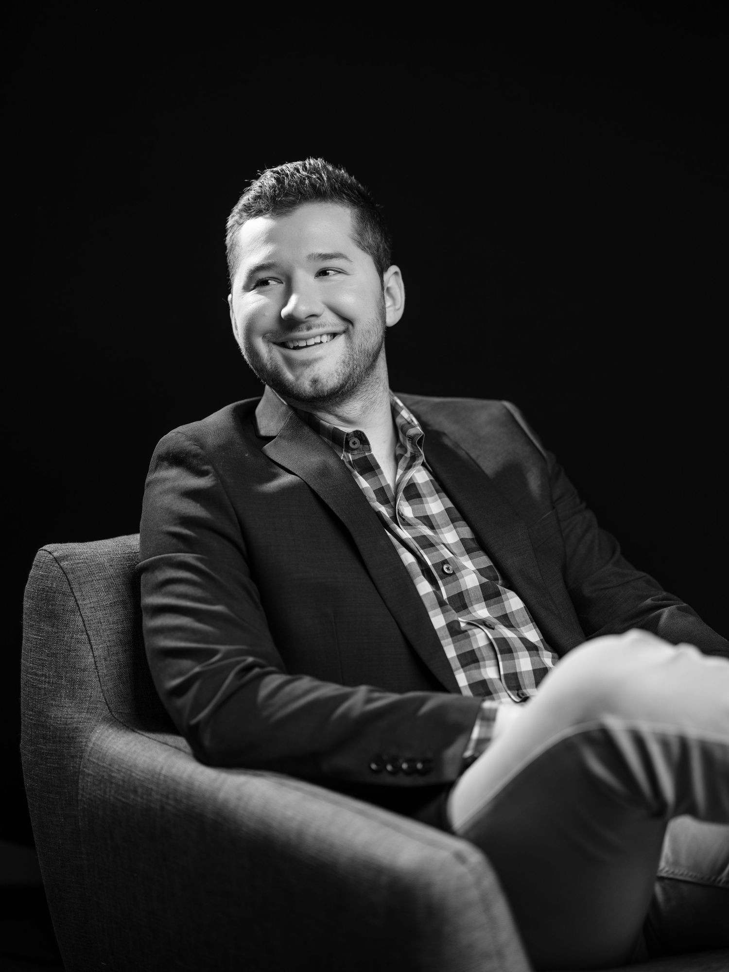 Black and white portrait series showing someone seated in a suit jacket and plaid shirt against dark background.