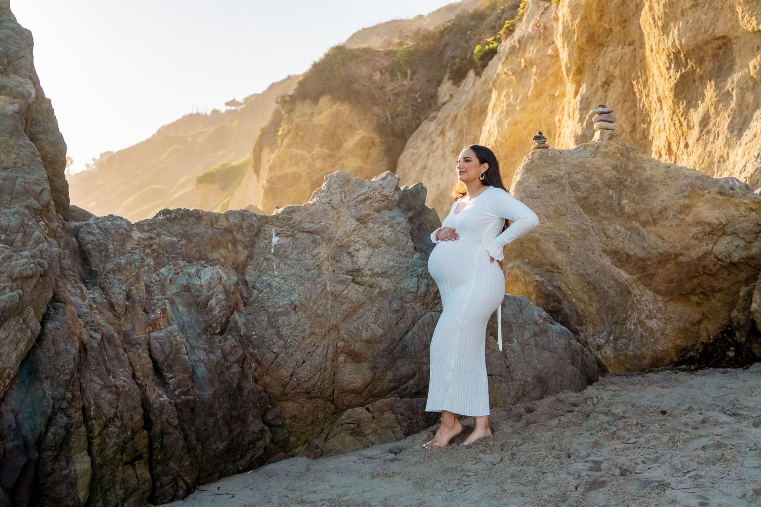 Elegant maternity portrait against dramatic coastal cliffs at sunset. malibu.