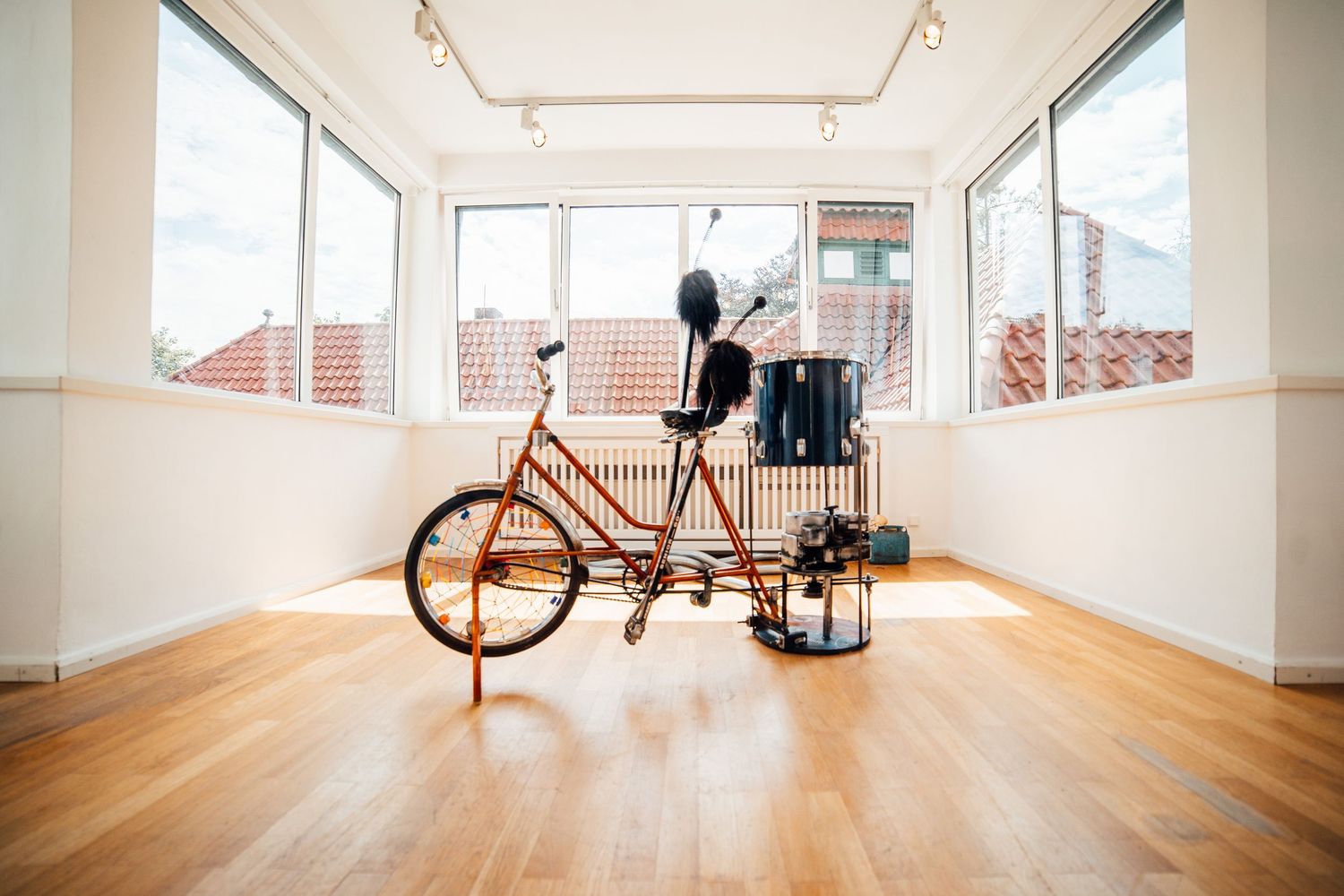 Vintage red tandem bicycle displayed in a bright modern gallery with large windows.