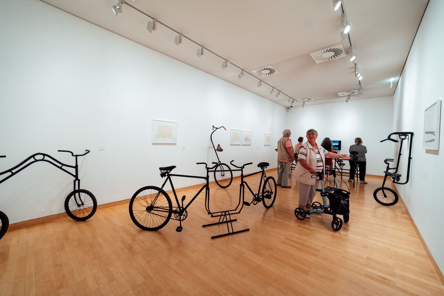 Museum gallery displaying artistic bicycle sculptures with visitors exploring the exhibition.