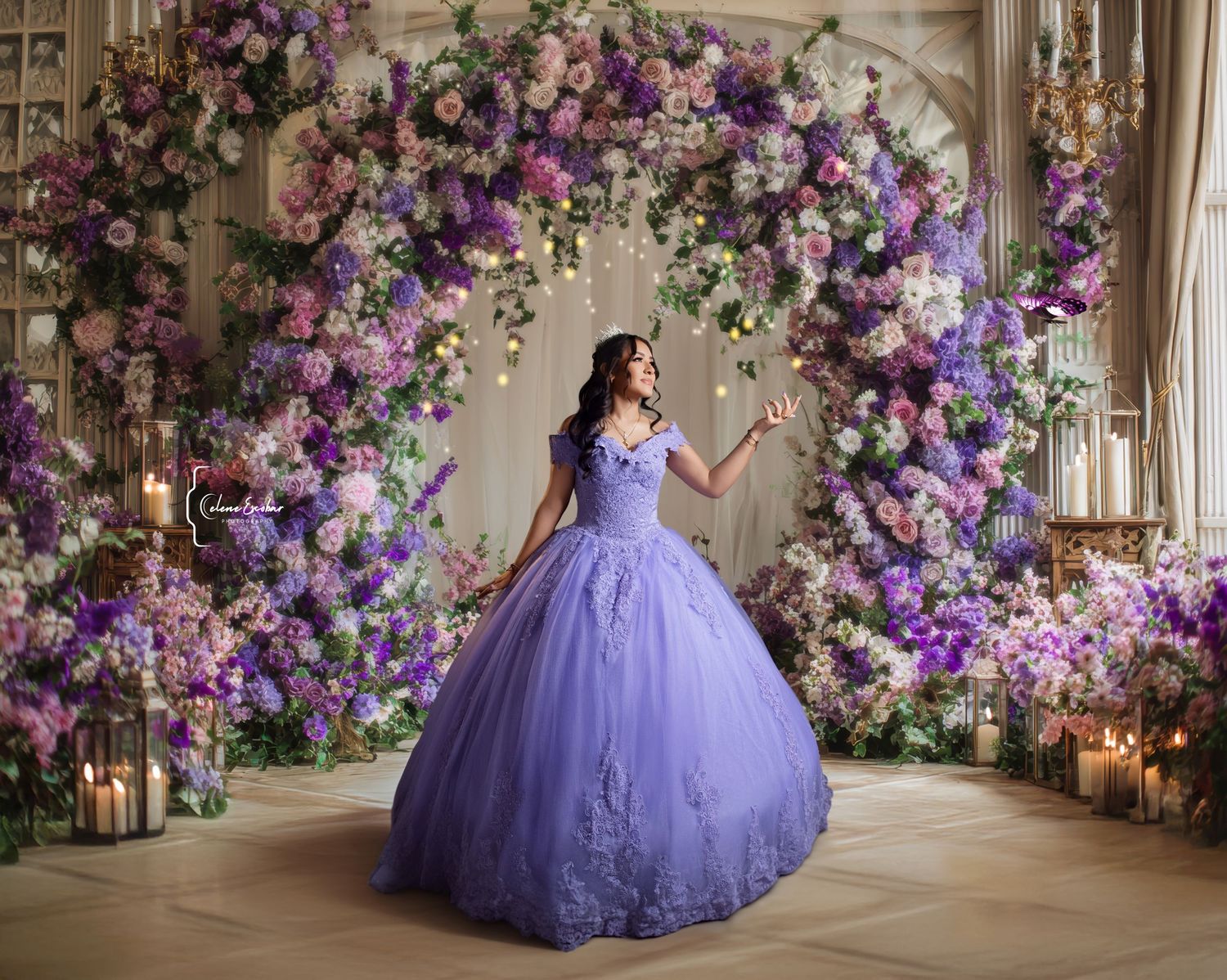 Woman in lavender ball gown poses before floral arch with purple blooms and candles in elegant setting.