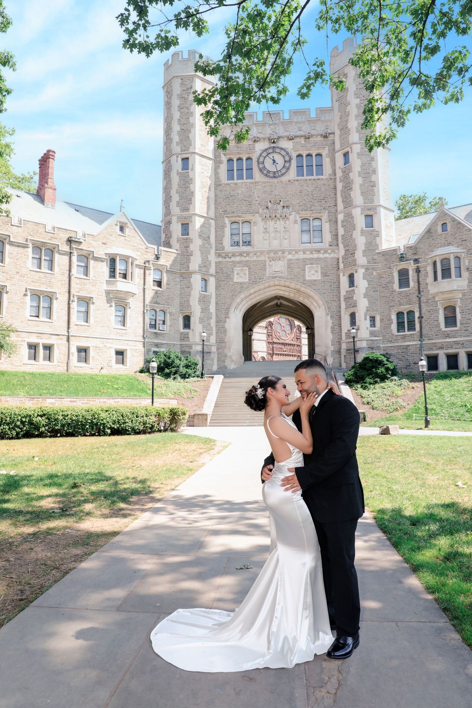 Newlyweds share romantic kiss in front of grand stone castle archway on wedding day.