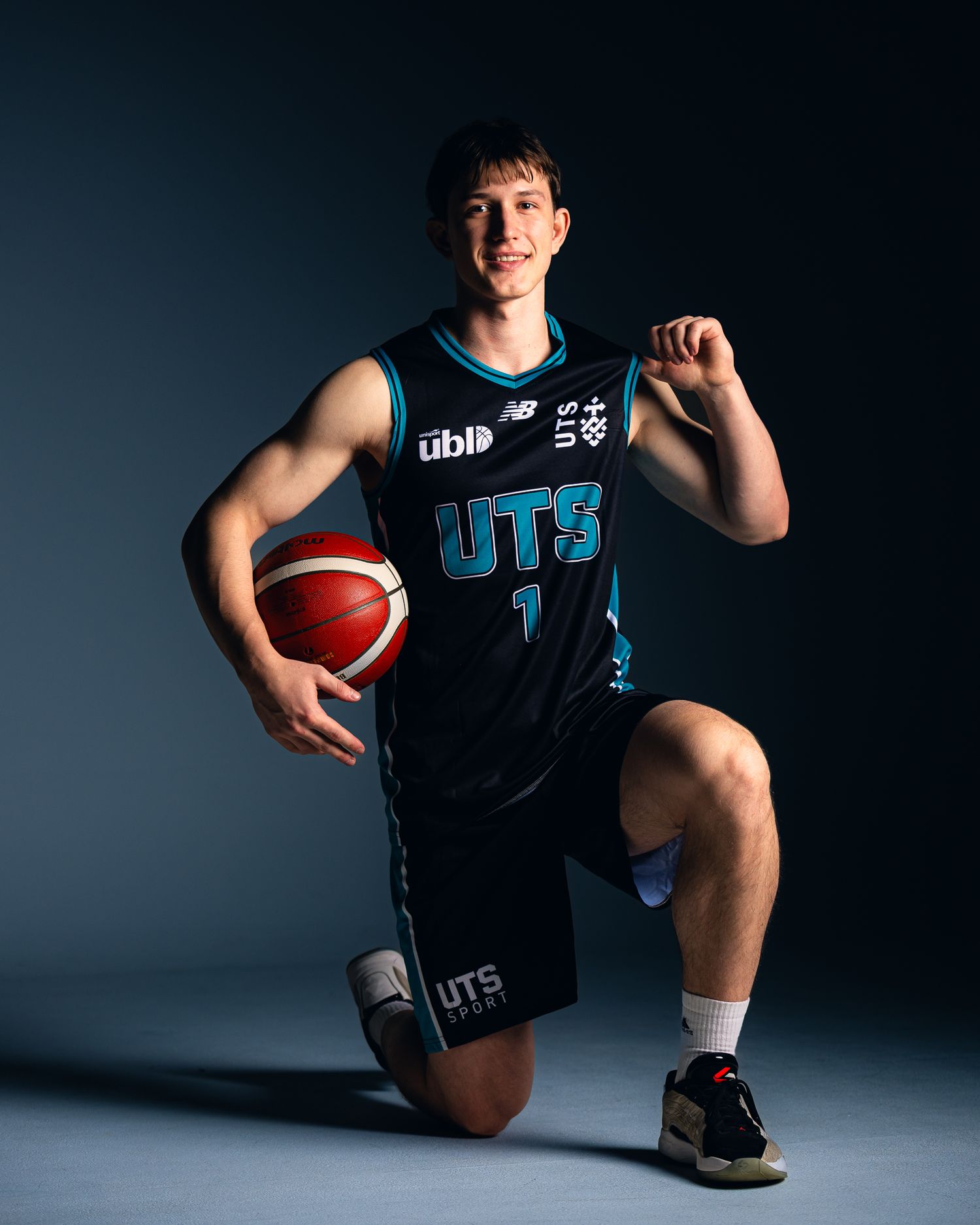 UTS Flames basketball player wearing jersey number 1 poses with a ball in a professional team photo.