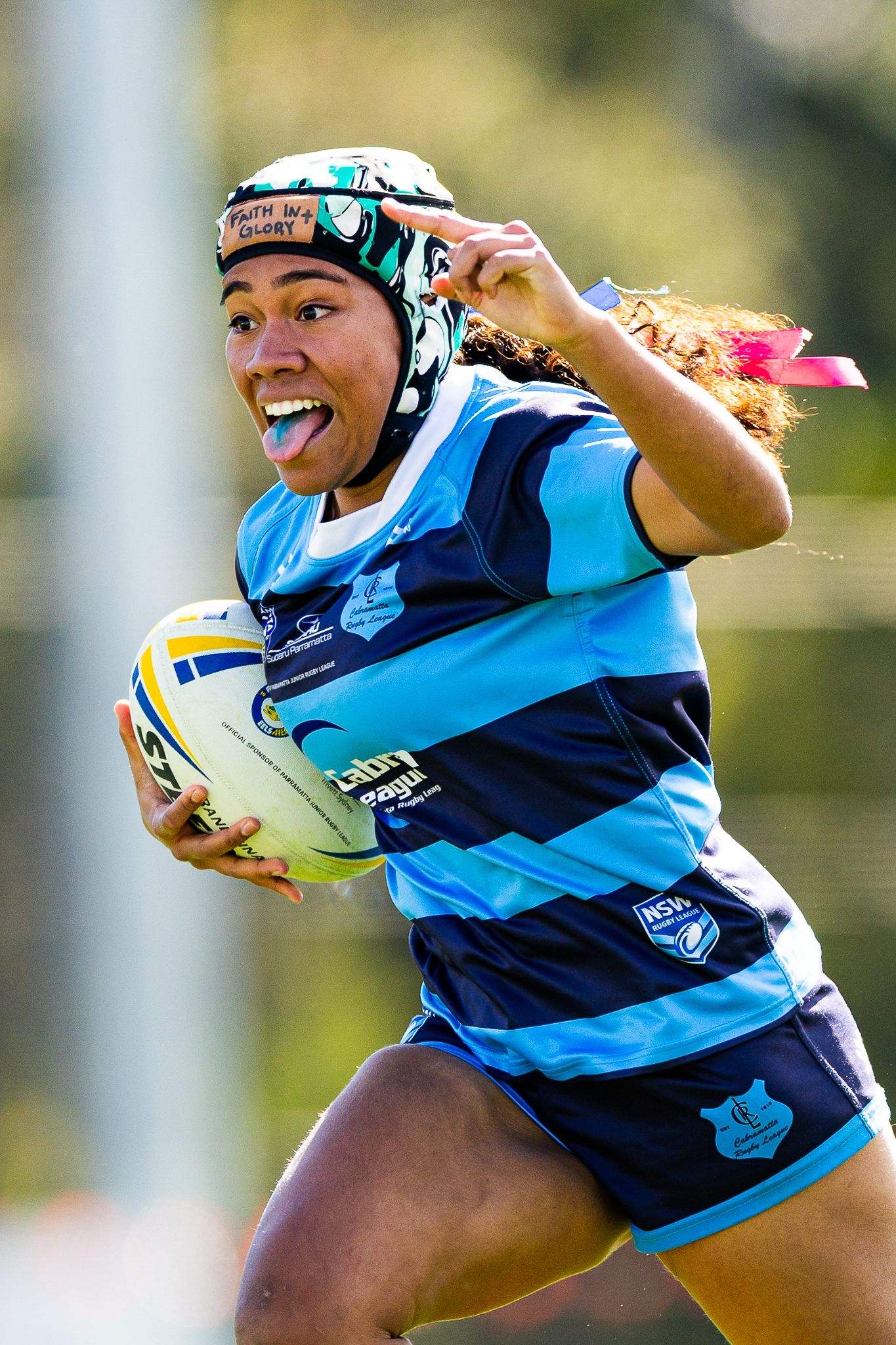 Rugby player in blue and navy uniform runs with ball during match action sequence.