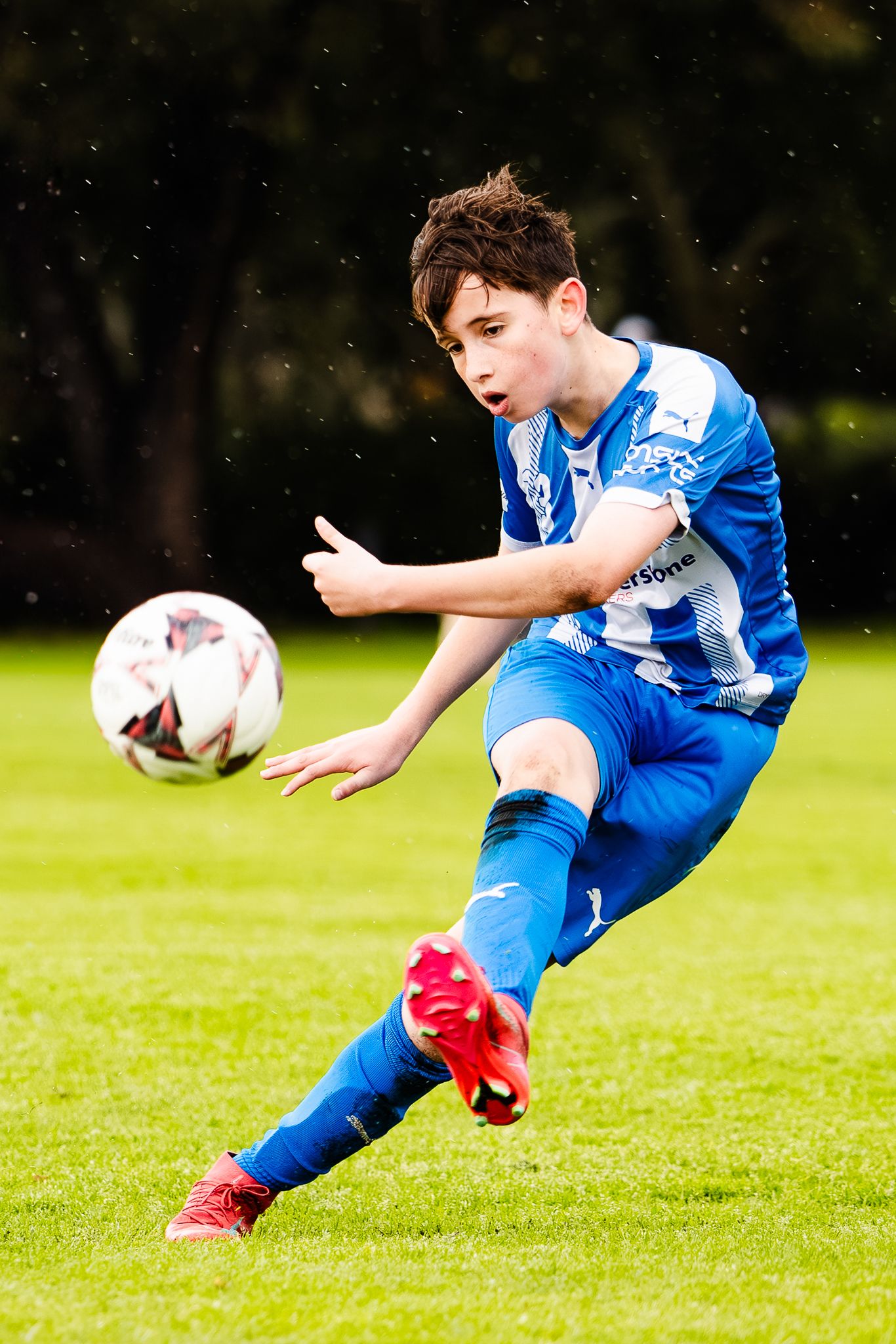 Soccer player in blue uniform diving to make a save on grass field during intense match action.