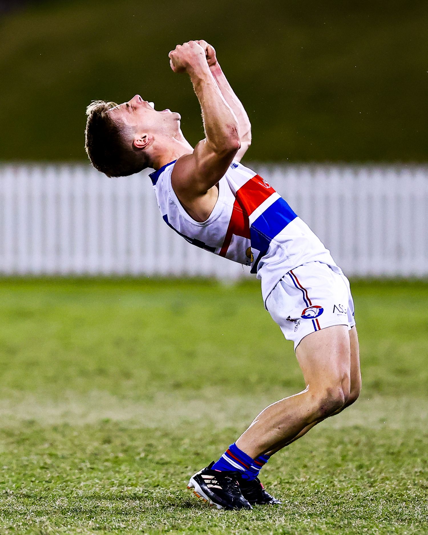 Soccer player writhes in pain on grass field after apparent injury during match.