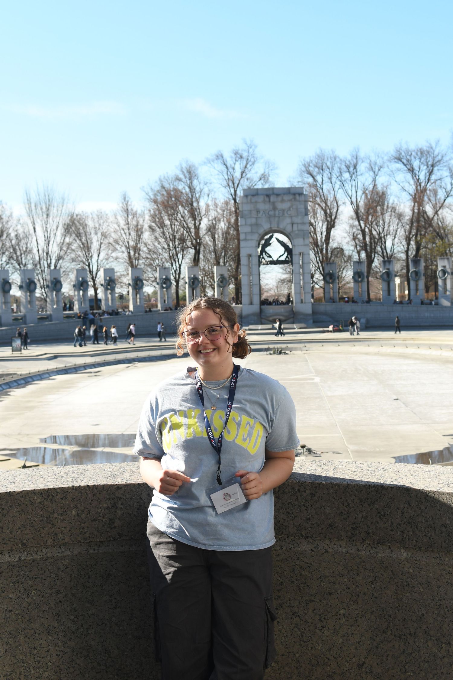Person in gray t-shirt stands at historic monument plaza on sunny day.