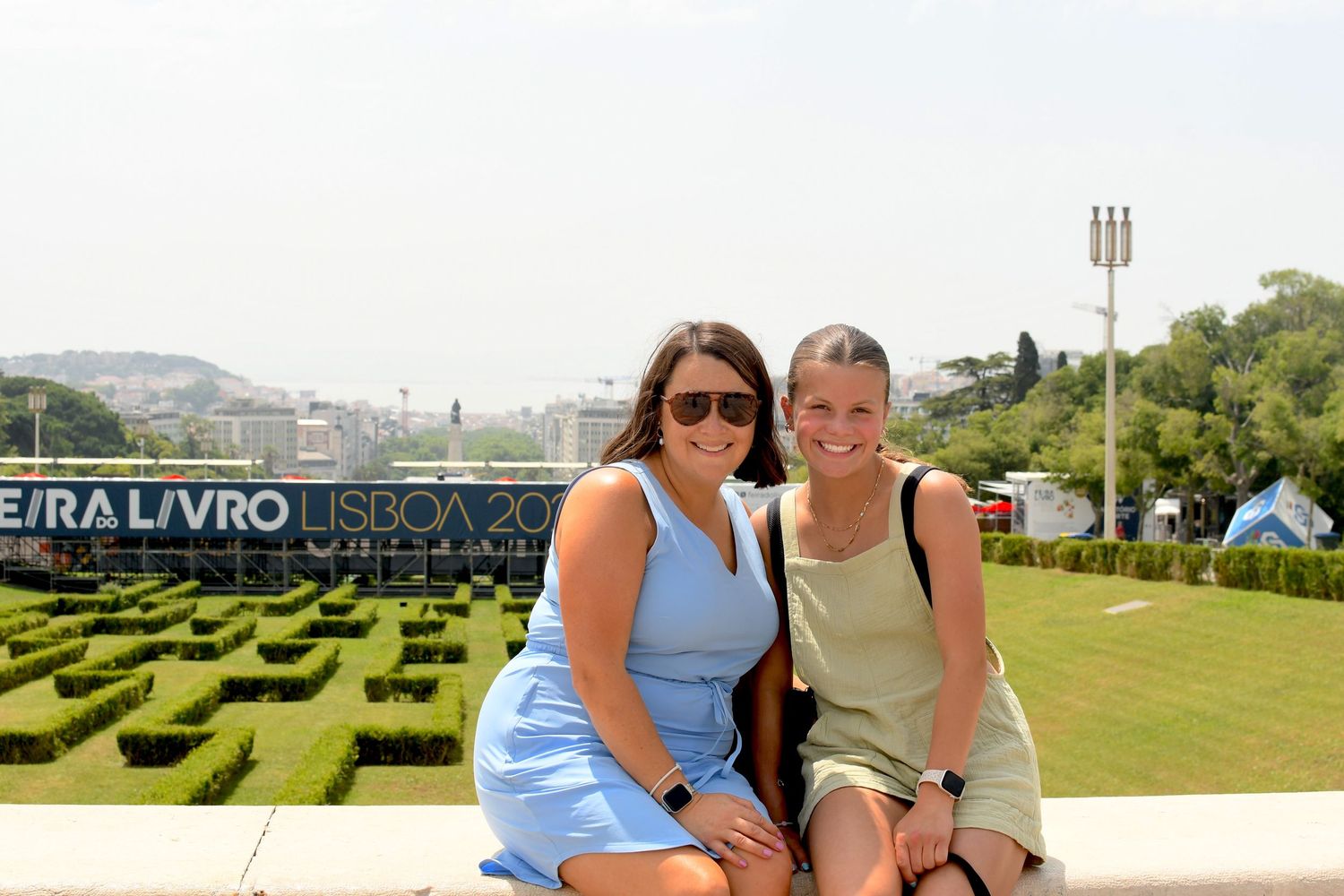 People enjoying a sunny day at a scenic overlook with large letters in the background.