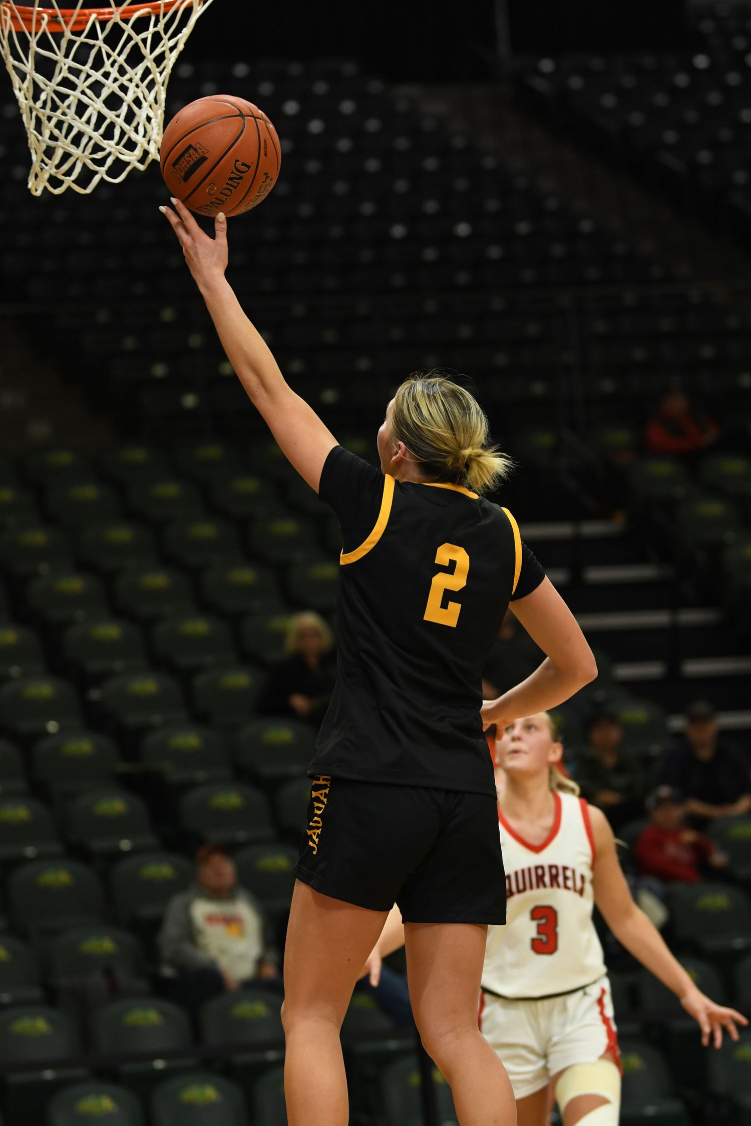 Basketball player in black jersey makes layup attempt at the basket.