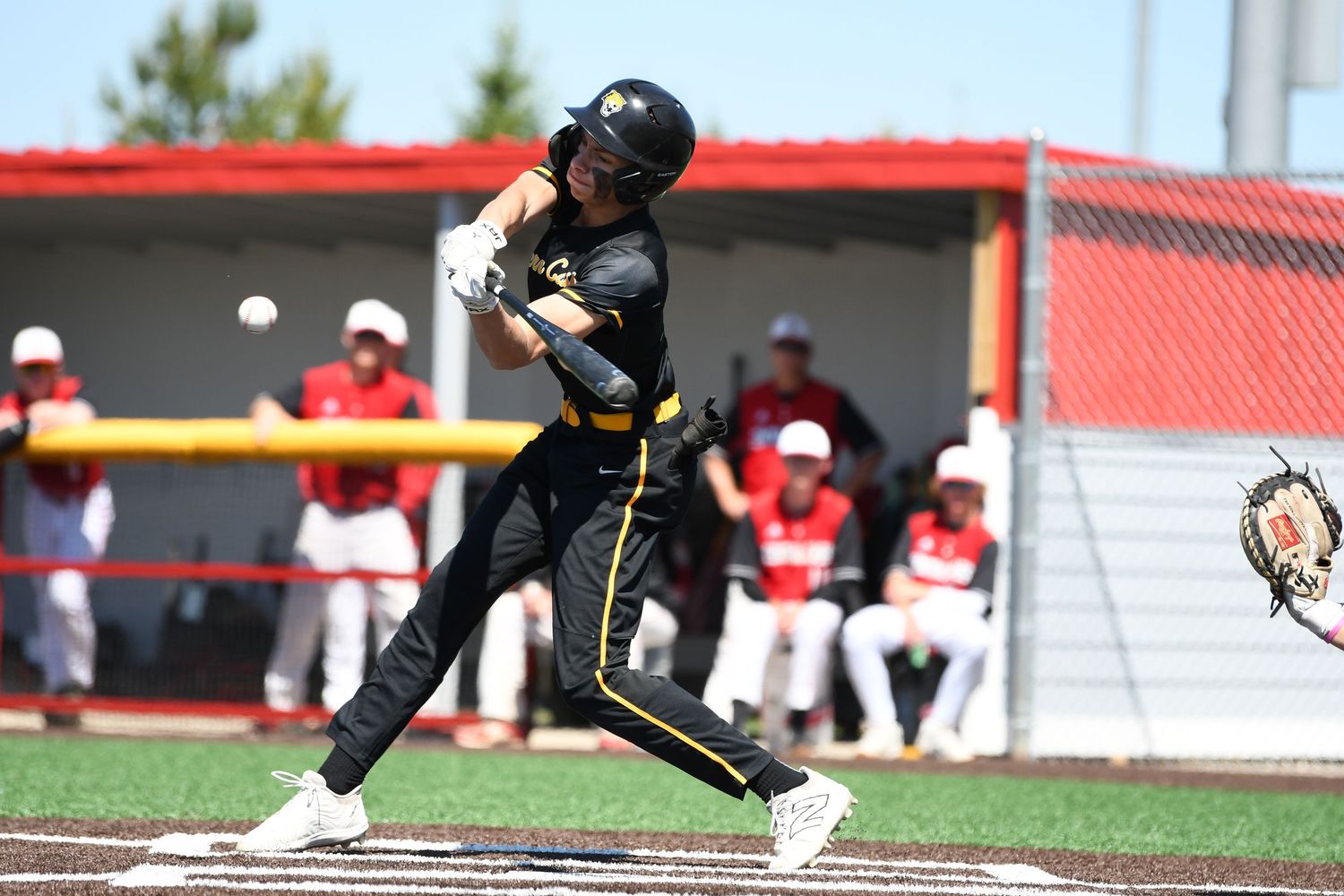 Baseball player in black uniform slides into base during competitive game.