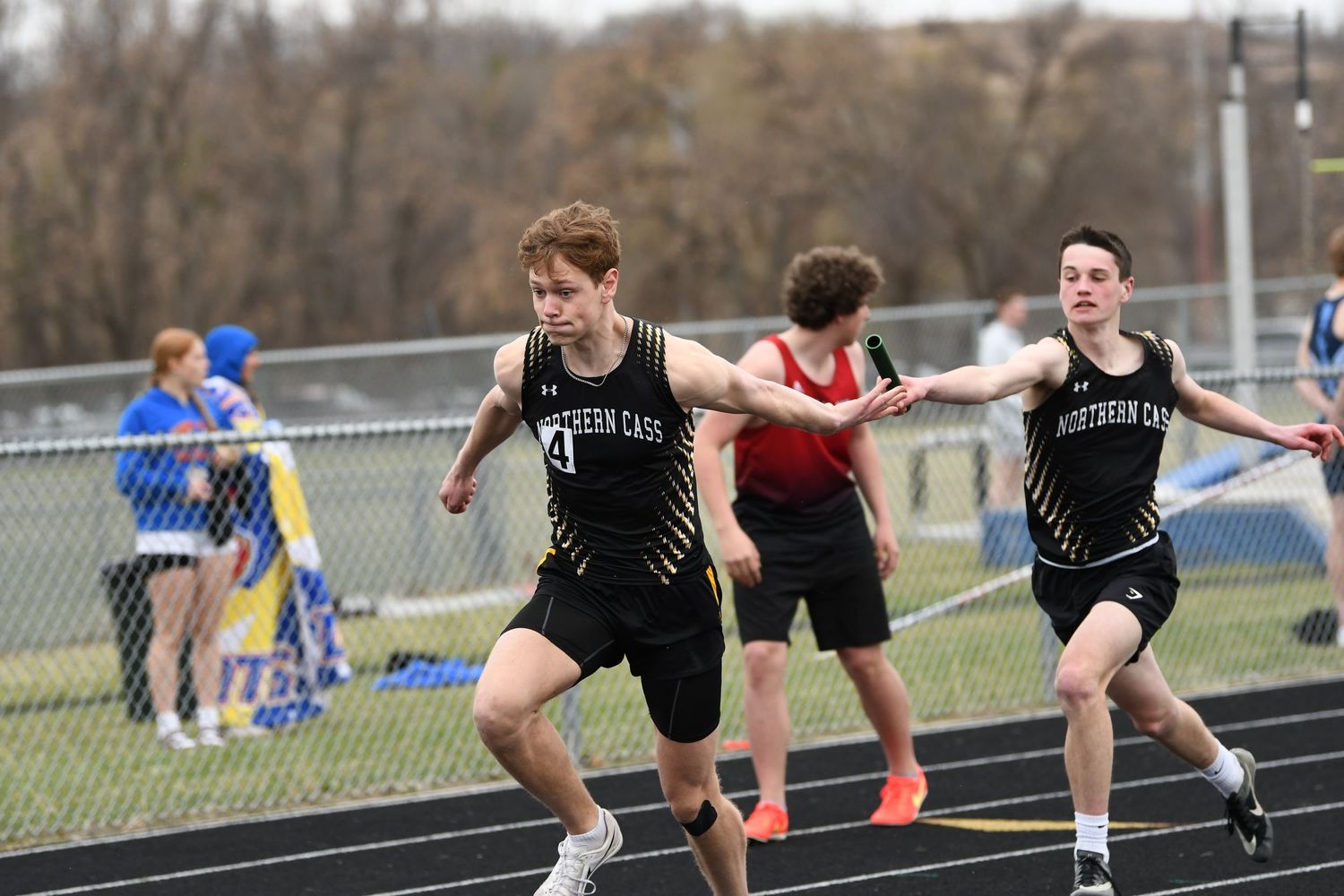 Athletes compete in close sprint race on outdoor track.
